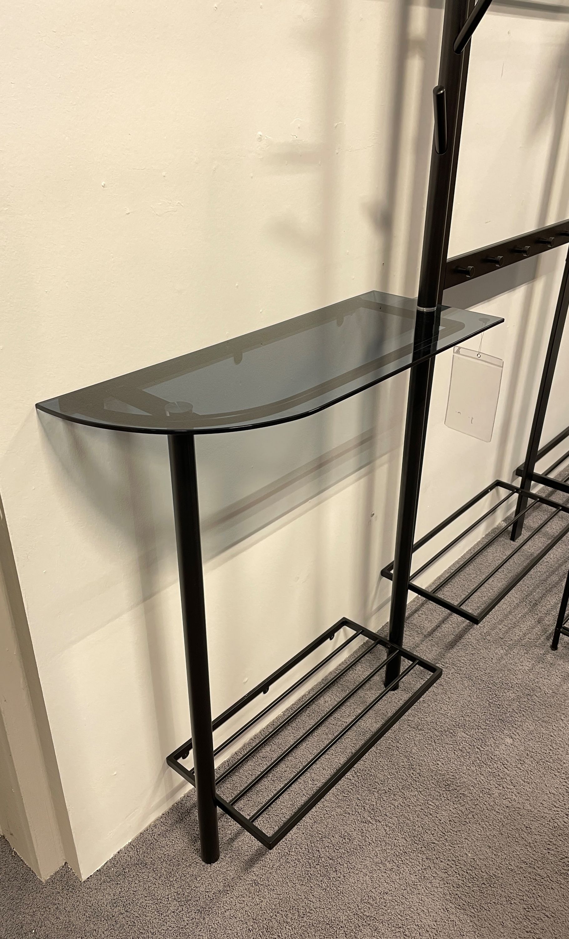 Glasablage mit schwarzem Metallgestell Halbrunde Glasablage mit schwarzem Metallgestell und unterem Ablagerost, geeignet für Flur oder Garderobe.