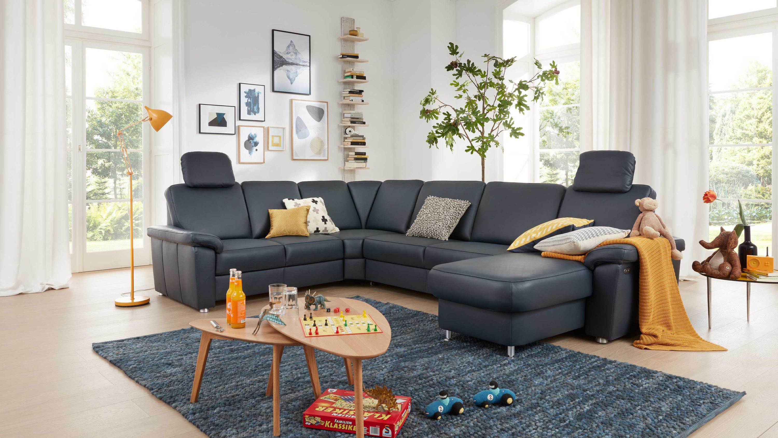 Ecksofa in nachtblauem Leder mit Metallfüßen in hellem Wohnzimmer mit Teppich und Beistelltischen