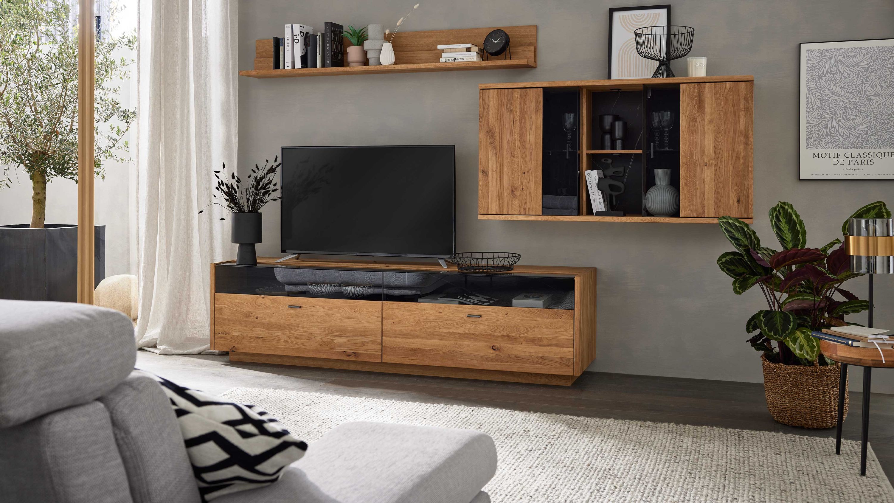 Dreiteilige Wohnwand aus Holz mit Glasfront Dreiteilige Wohnwand aus Holz mit zwei geschlossenen Schränken und einem offenen Regal mit Glasfront in hellbrauner Farbe