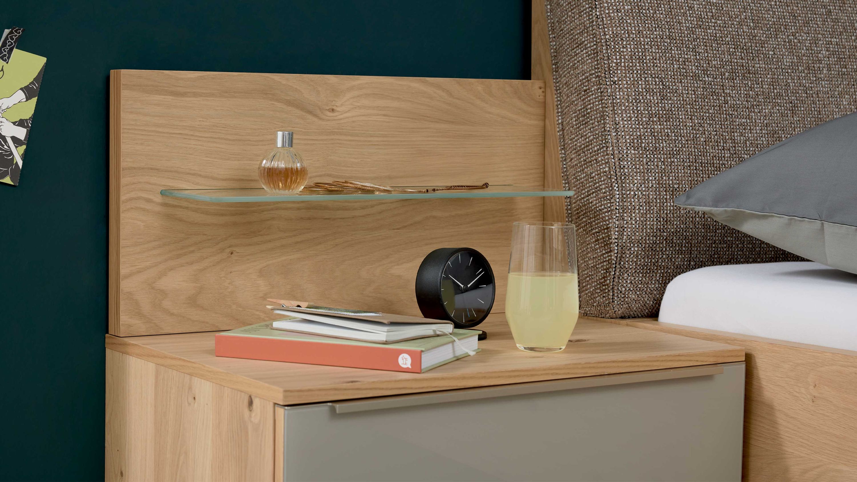 Nachttisch mit Holzpaneel und Glasablage darauf Uhr Bücher und Glas mit Getränk