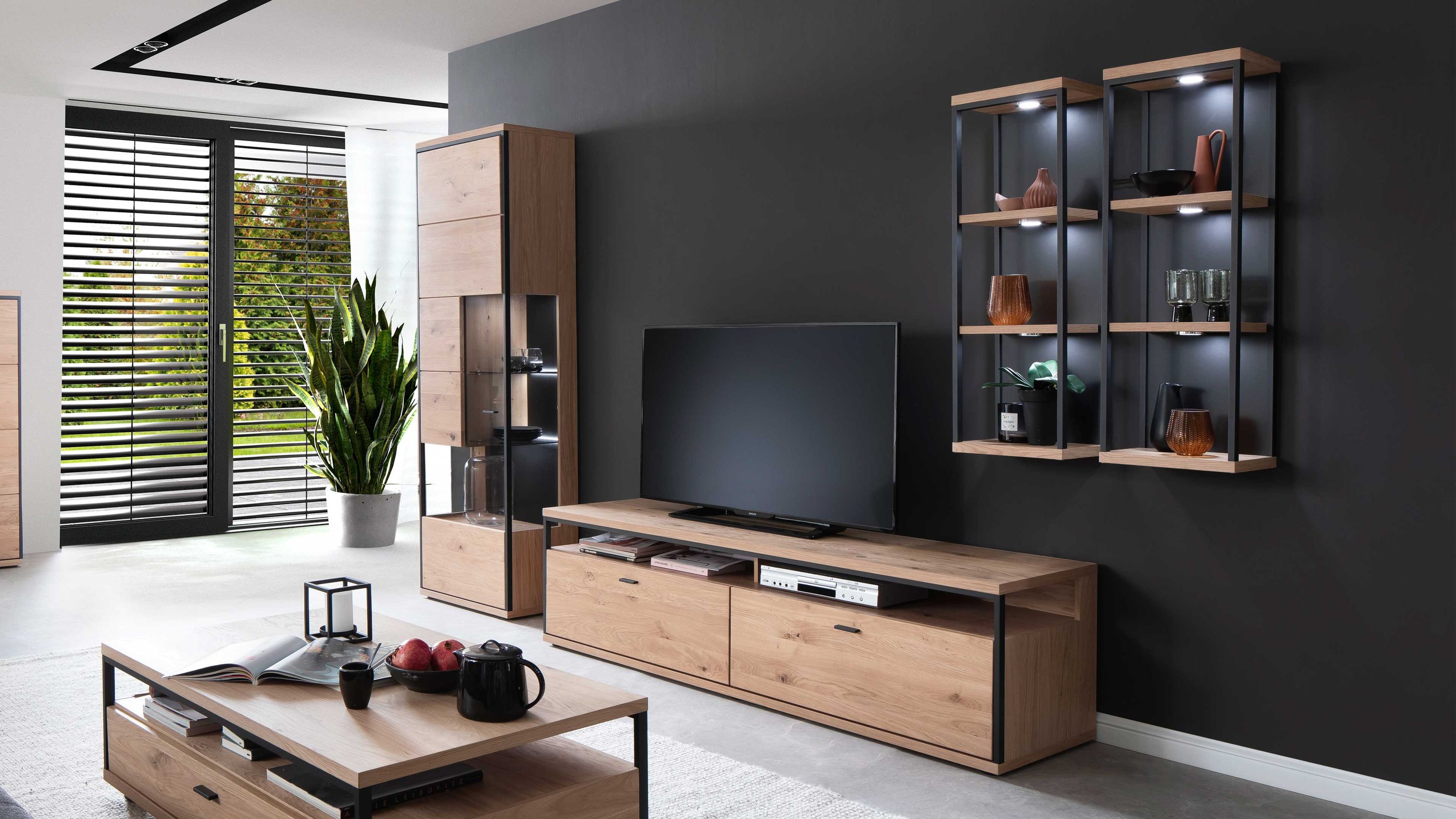 Wohnwand aus hellem Holz mit schwarzen Metallrahmen: TV-Board, Vitrine, zwei Wandregale und Couchtisch