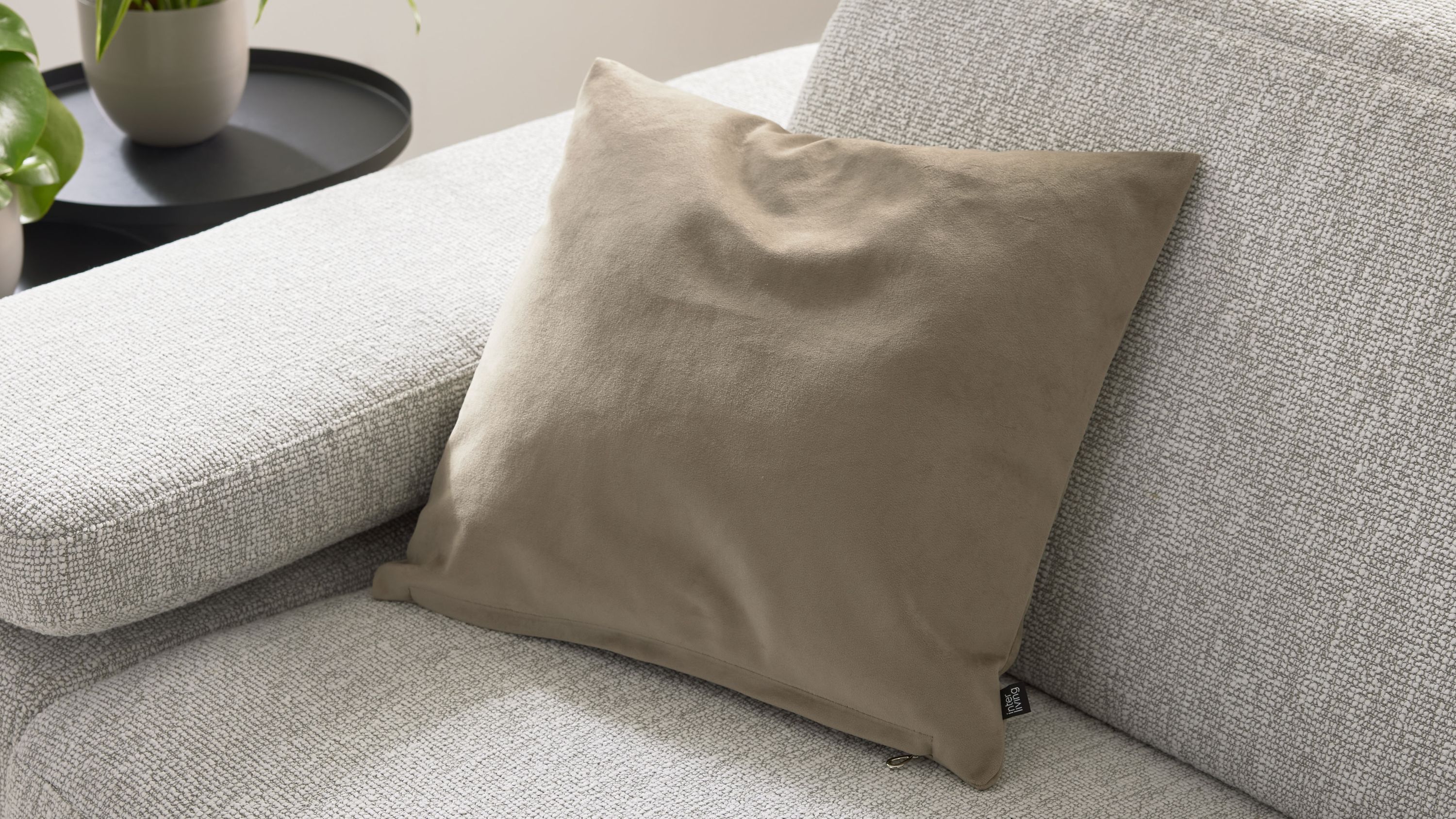 Quadratische Kissenhülle in taupe auf hellgrauem Sofa