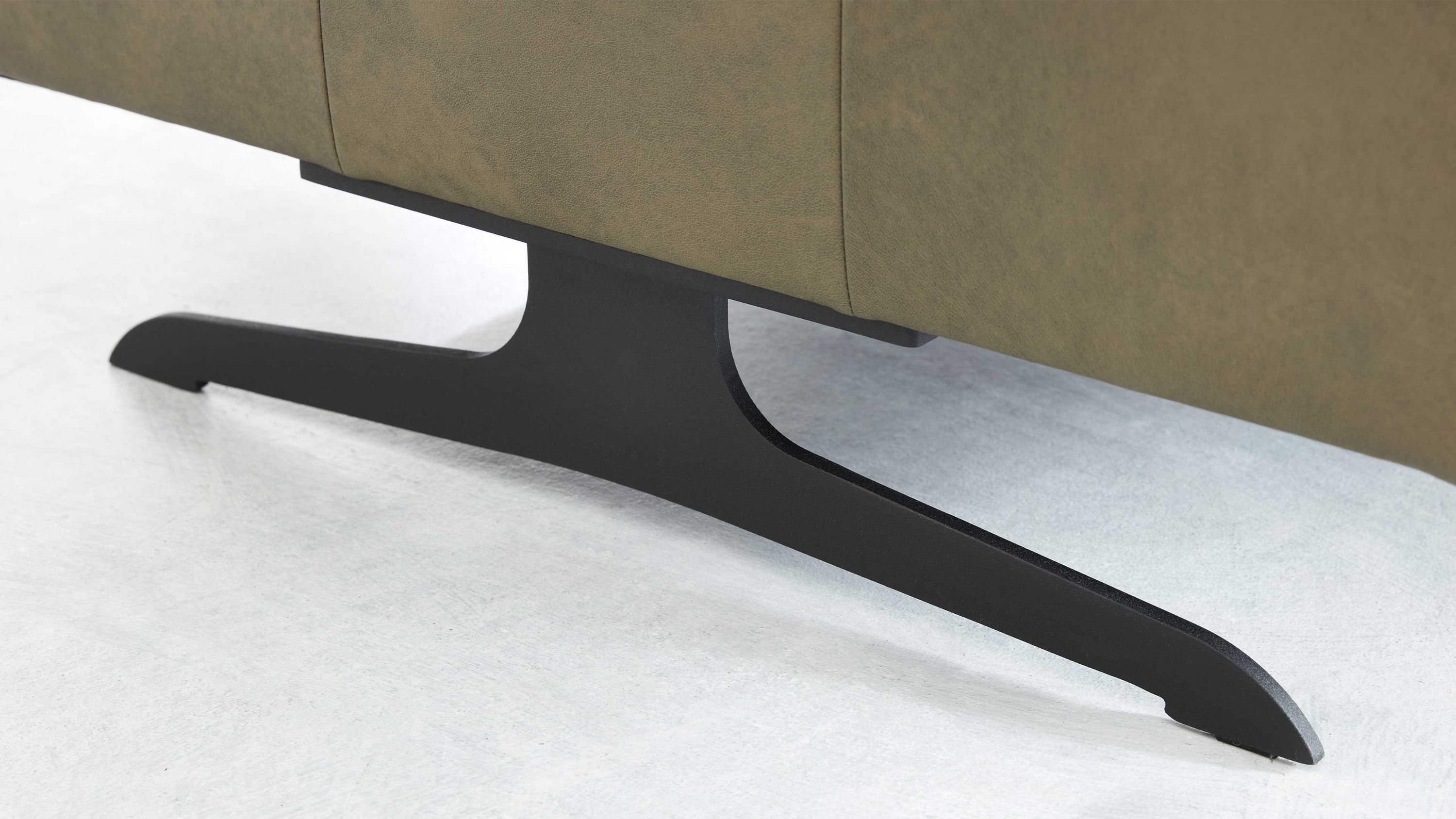 Mattschwarze Metallkufe mit flacher gebogener Form unter einem Sofa