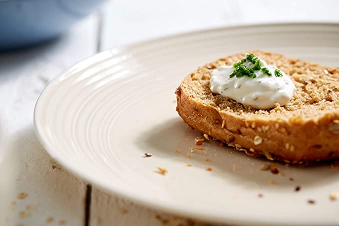 16-teiliges Tafelservice in Blau mit Frühstücksteller Scheibe Körnerbrot mit Creme und Schnittlauch auf beigem Teller, leicht erhöht auf hellem Holztisch fotografiert