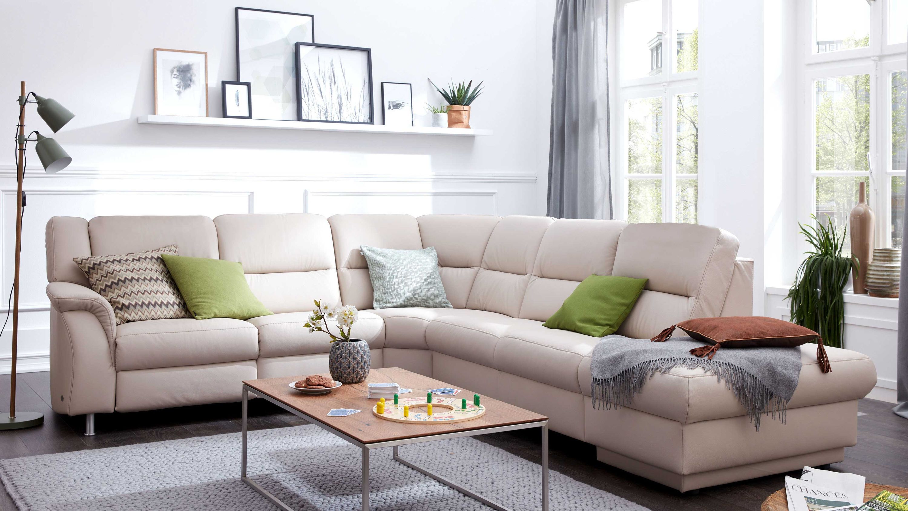 Ecksofa in marmorfarbenem Leder mit Kissen in grün grau und braun in einem hellen Wohnzimmer