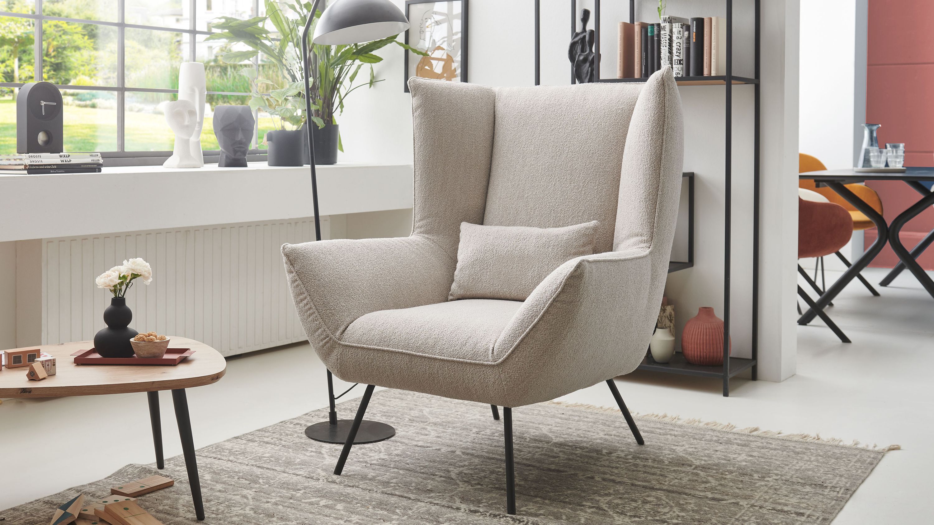 Lounge-Polstersessel mit sandfarbenem Bezug hoher Rückenlehne und schwarzen Metallfüßen in modernem Wohnzimmer
