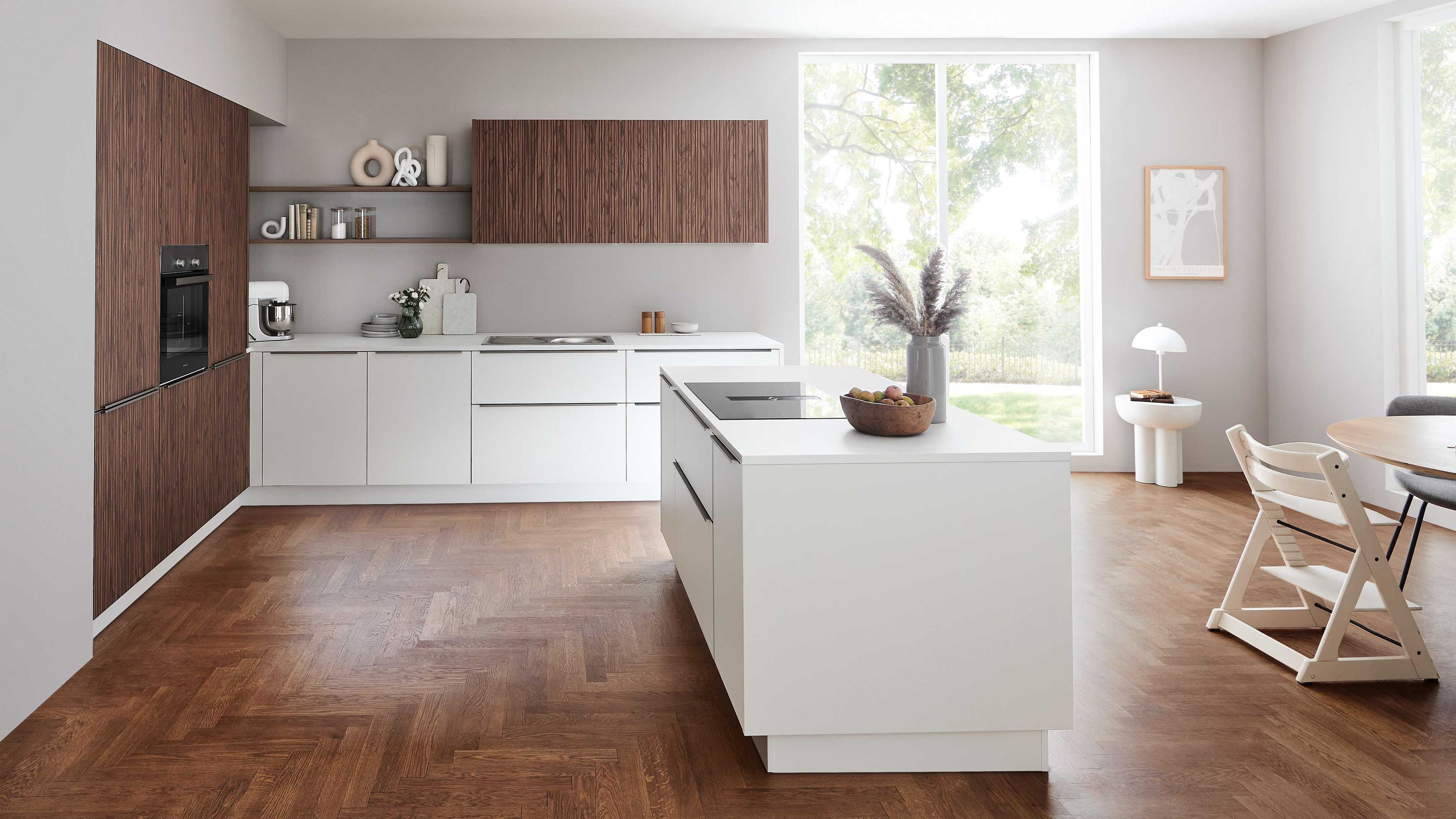 Weiße Küche mit Holzdetails Insel Fischgrätboden Rundtisch großen Fenstern Tageslicht Küchenutensilien.