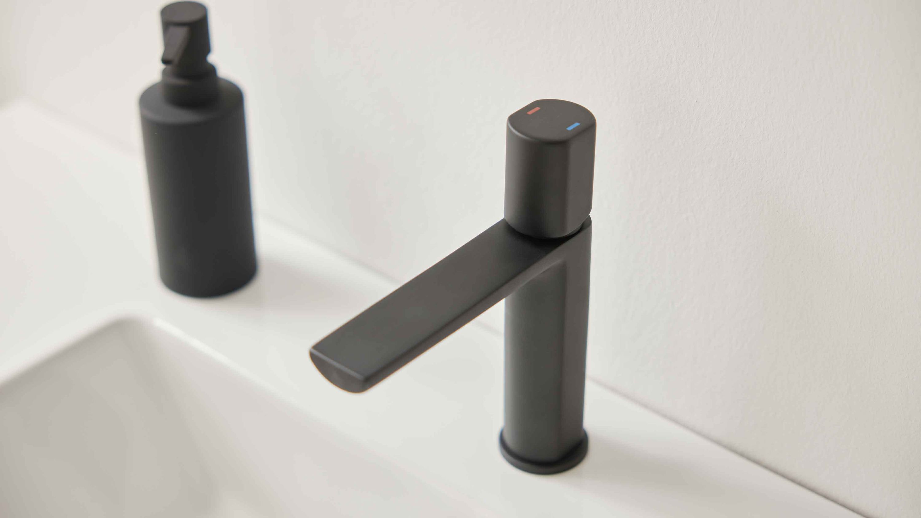 Matte Armatur in dunkler Farbe mit Hebelgriff auf weißem Waschbecken