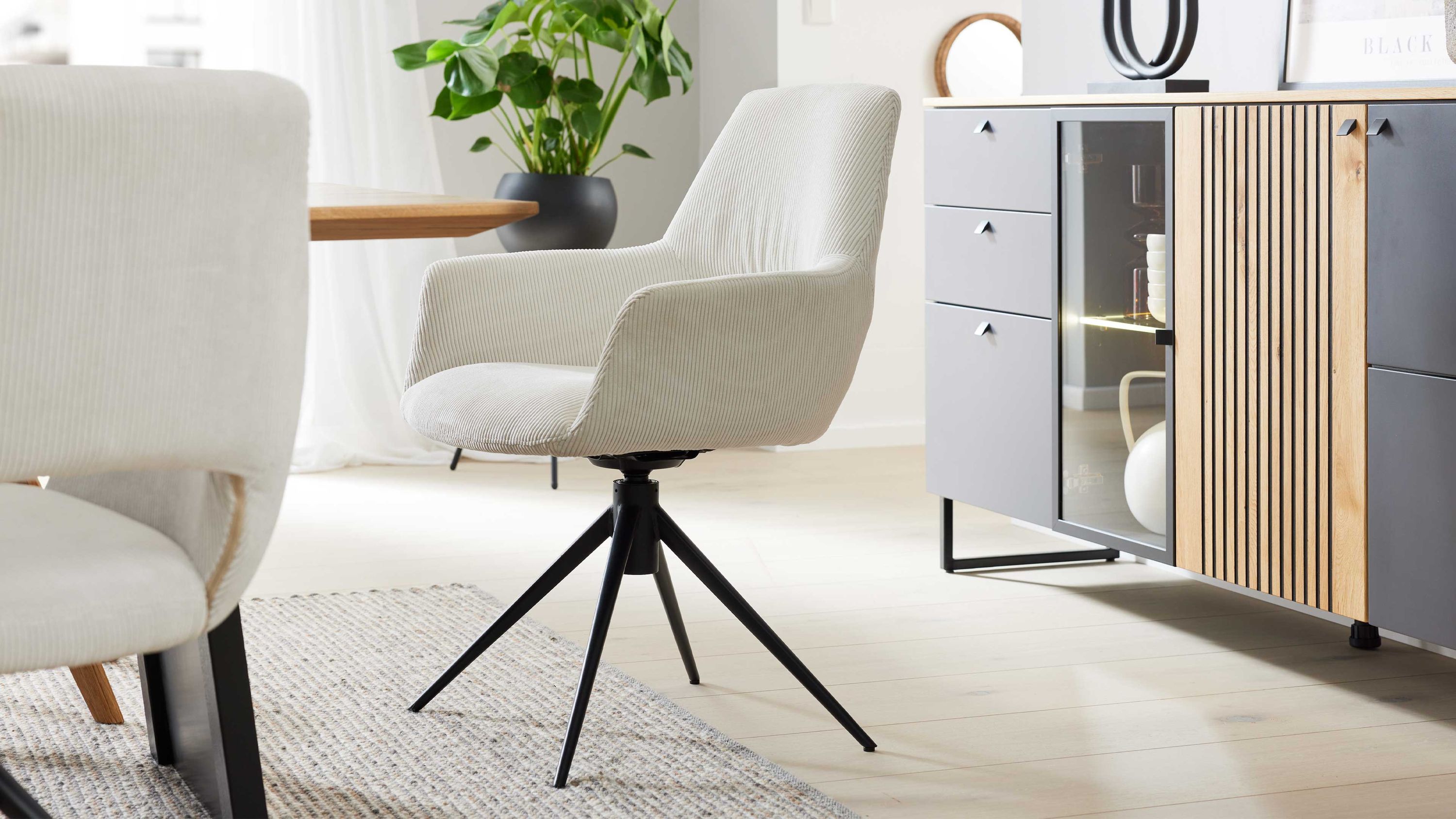Armlehnstuhl mit cremeweißem Cordbezug und schwarzem Metallgestell in modernem Esszimmer