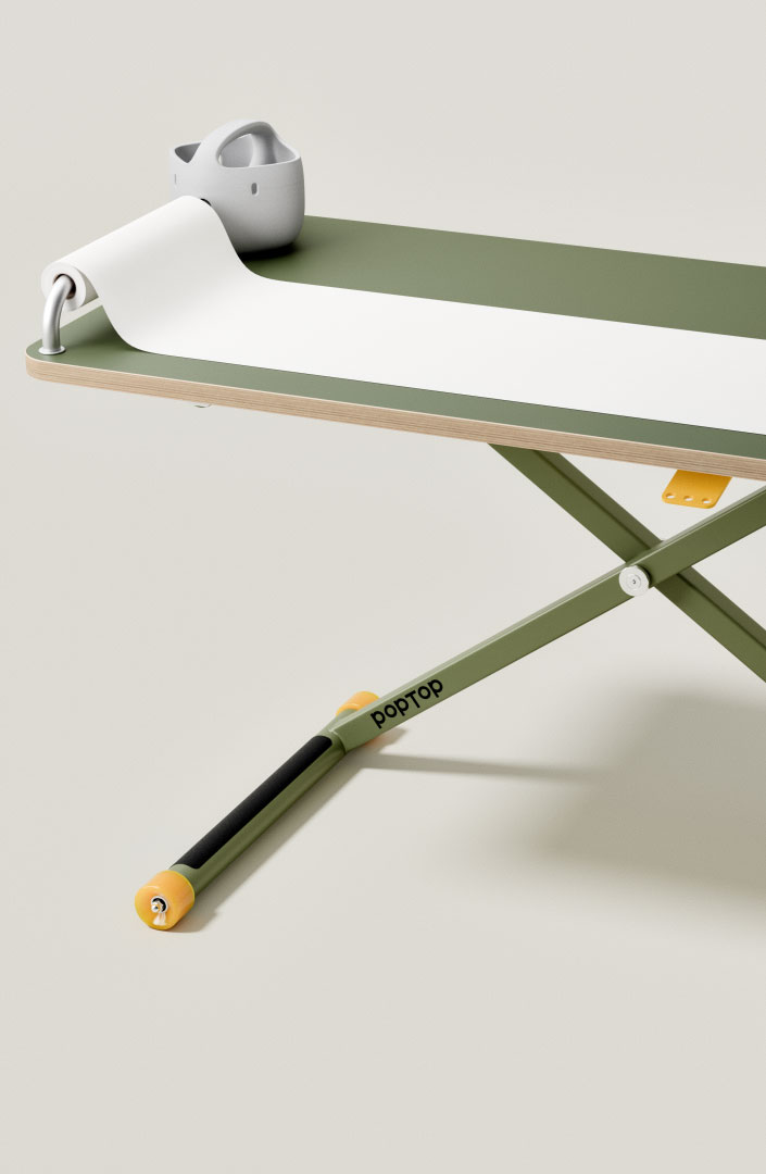 Schwarze Aluminiumstange mit gelben Enden an grünem Klapptisch mit Papierrolle befestigt.