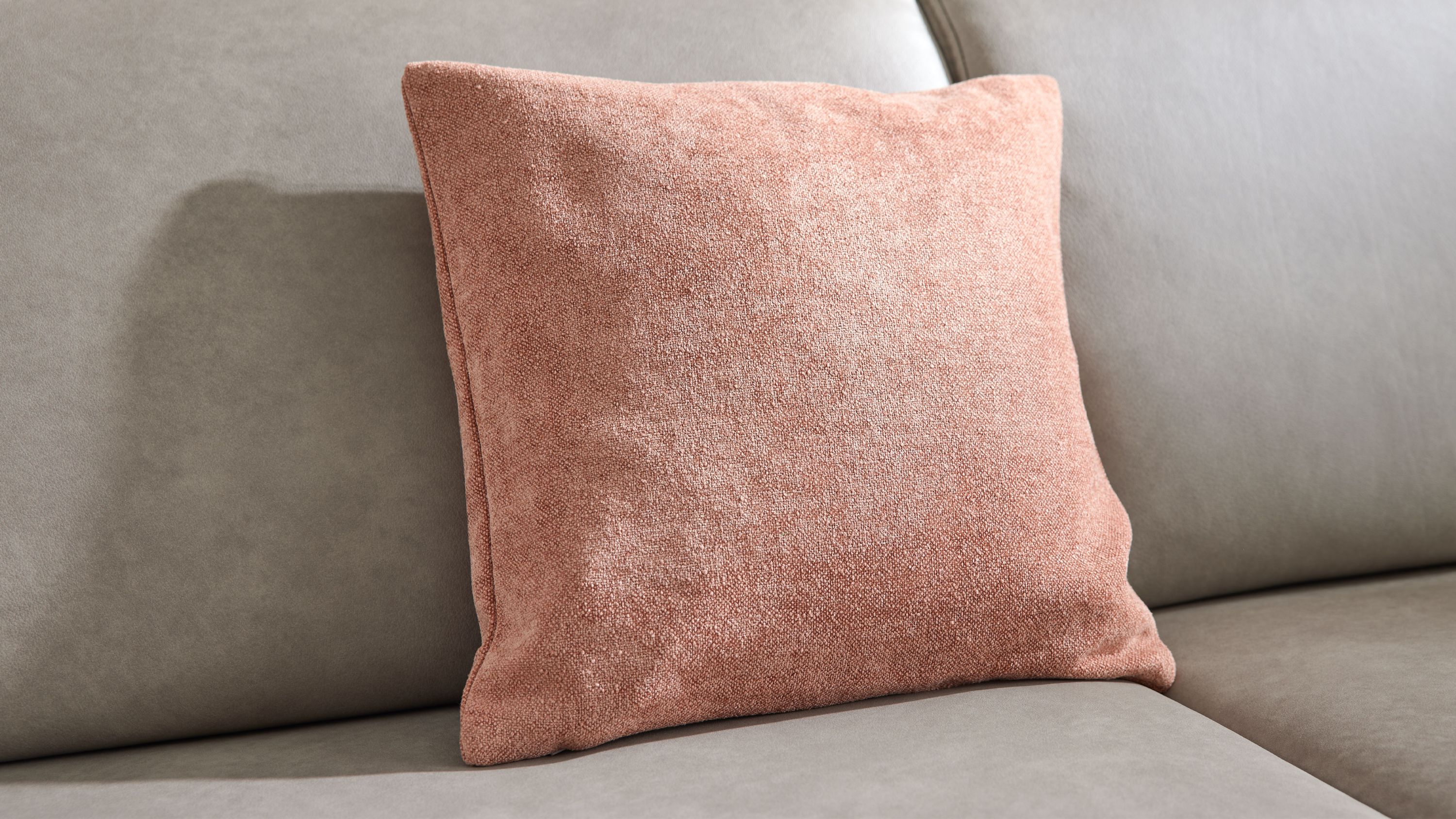 Rosafarbenes Kissen mit Chenille-Bezug auf Sofa Quadratisches Kissen mit rosafarbener Chenille-Kissenhülle auf grauem Sofa