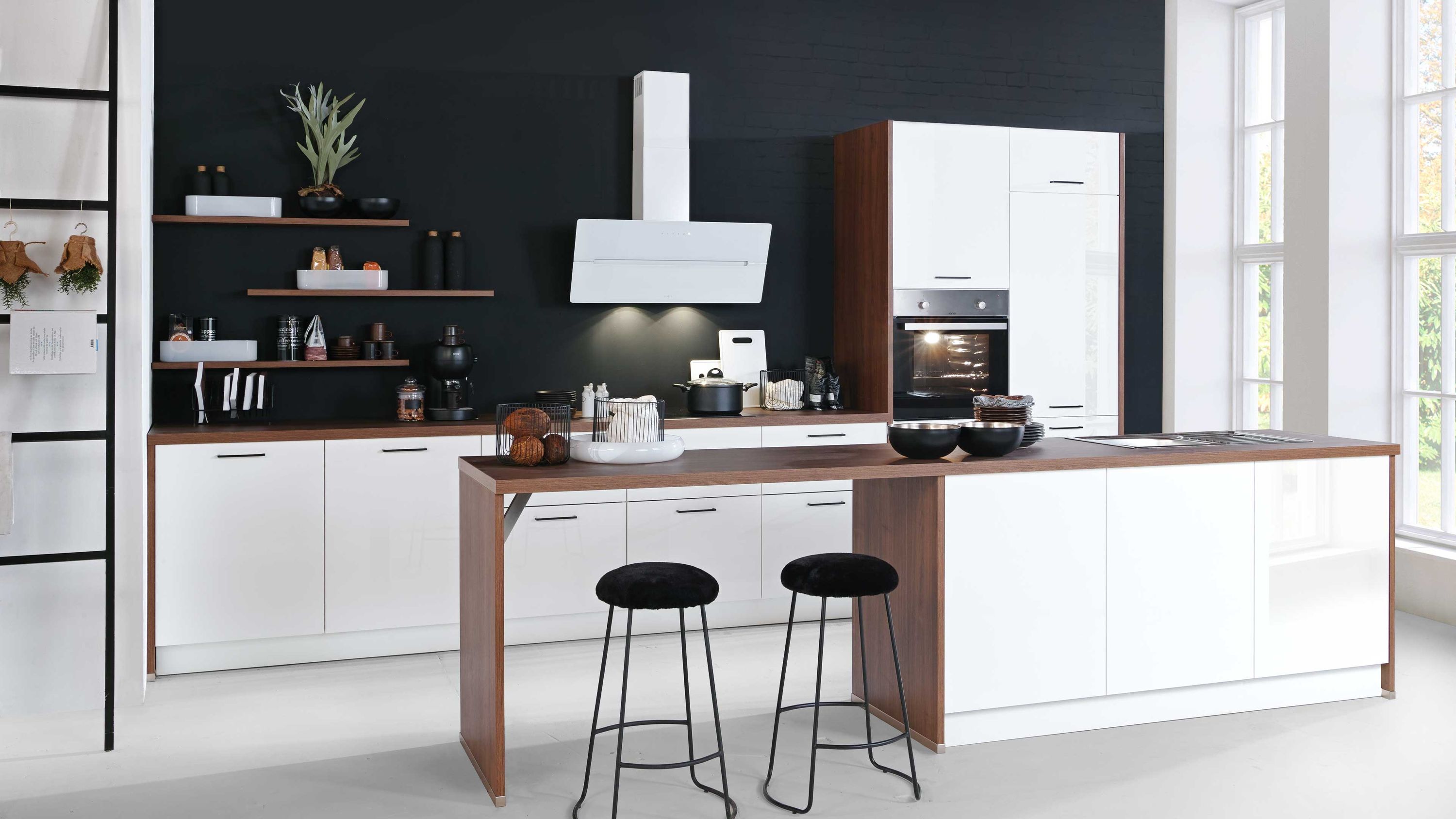 Küche mit weißen Fronten Holzdetails Insel mit schwarzen Hockern offenen Regalen und Fensterlicht