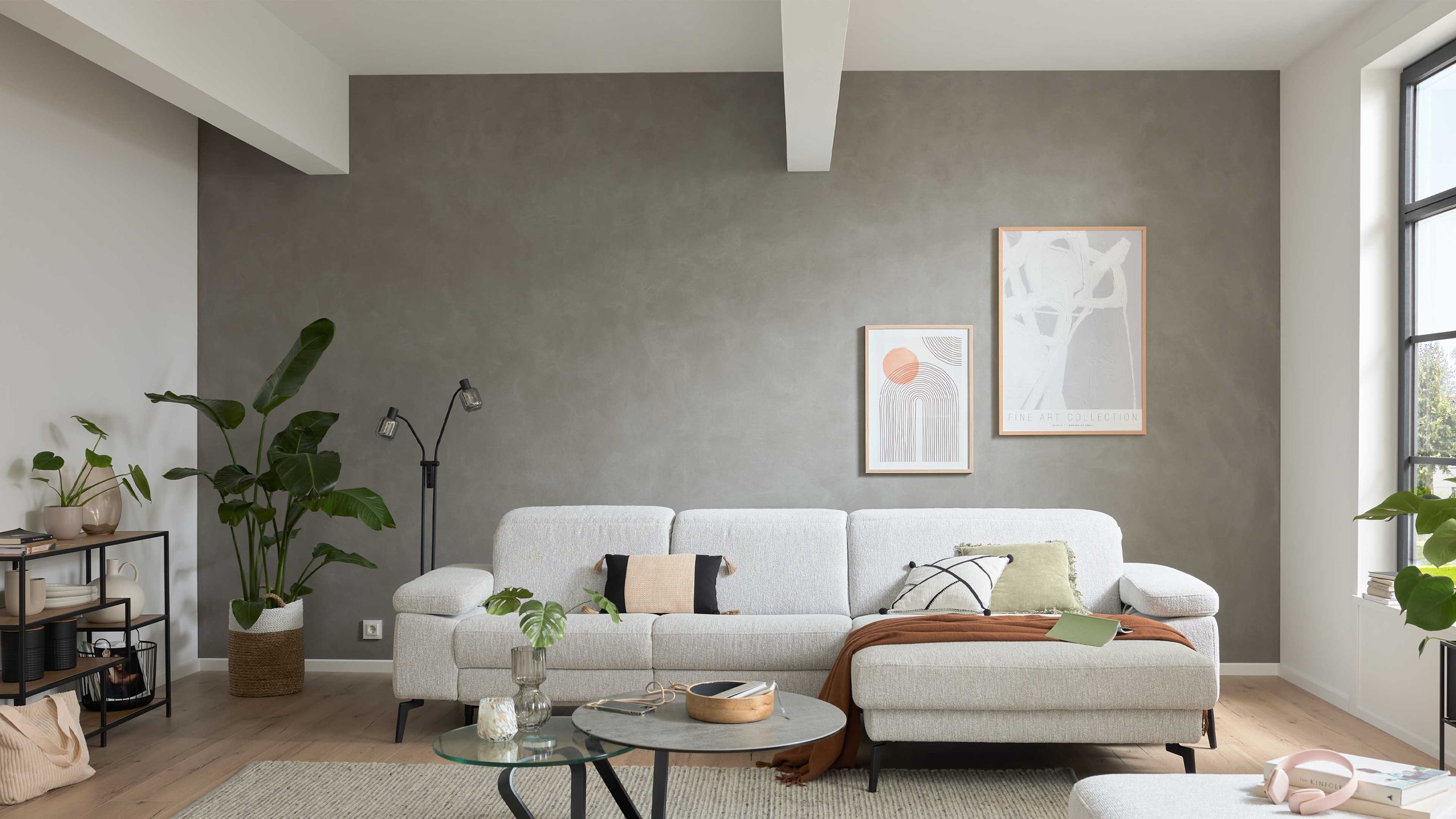 Ecksofa mit ecrufarbenem Webstoff und schwarzen Metallfüßen in modernem Wohnzimmer mit grauer Wand