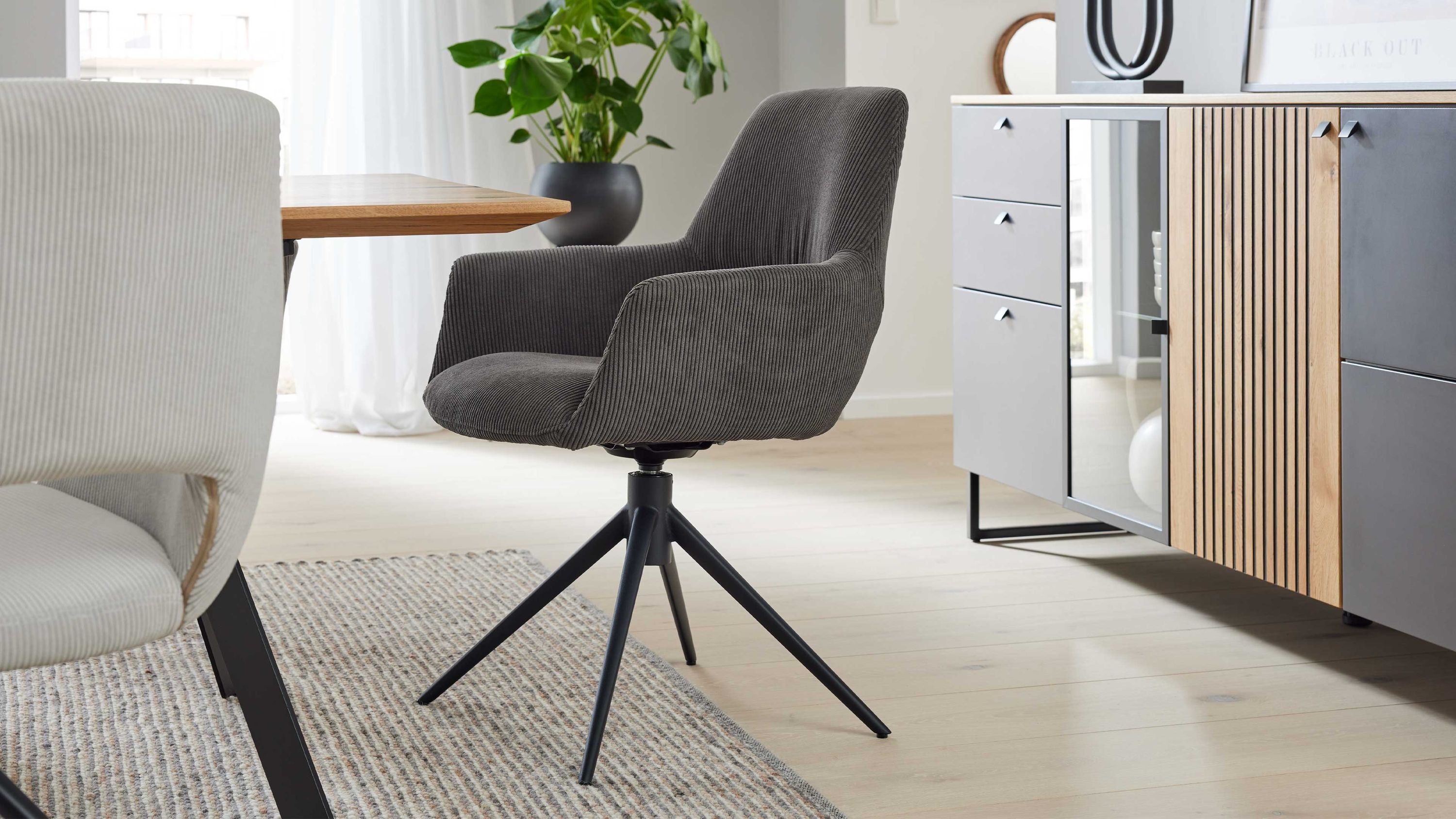 Drehbarer Armlehnstuhl mit anthrazitfarbenem Cordbezug und schwarzem Metallgestell in modernem Esszimmer