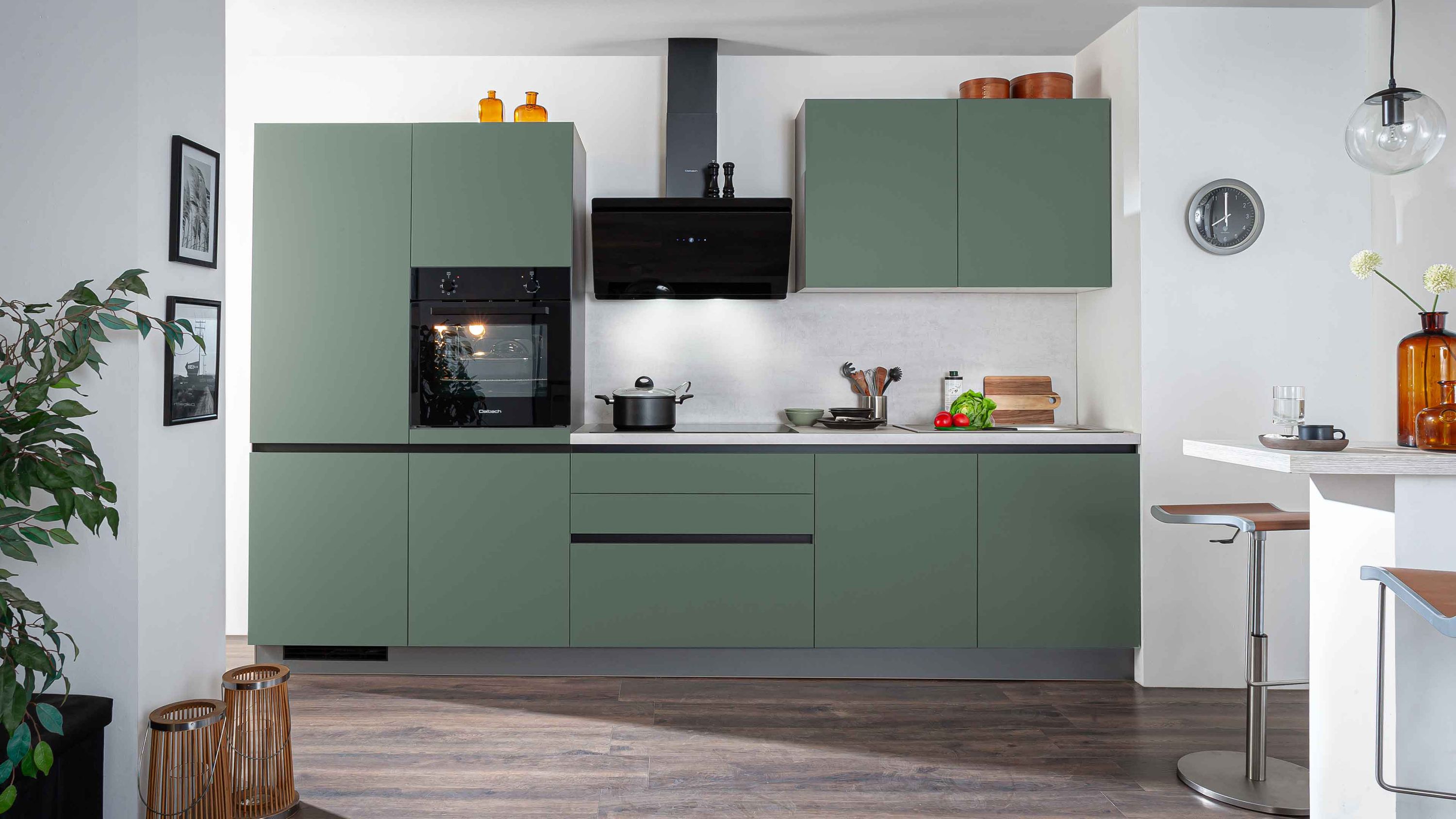 Moderne Küche in Mattgrün mit schwarzer Arbeitsplatte und Dunstabzugshaube.