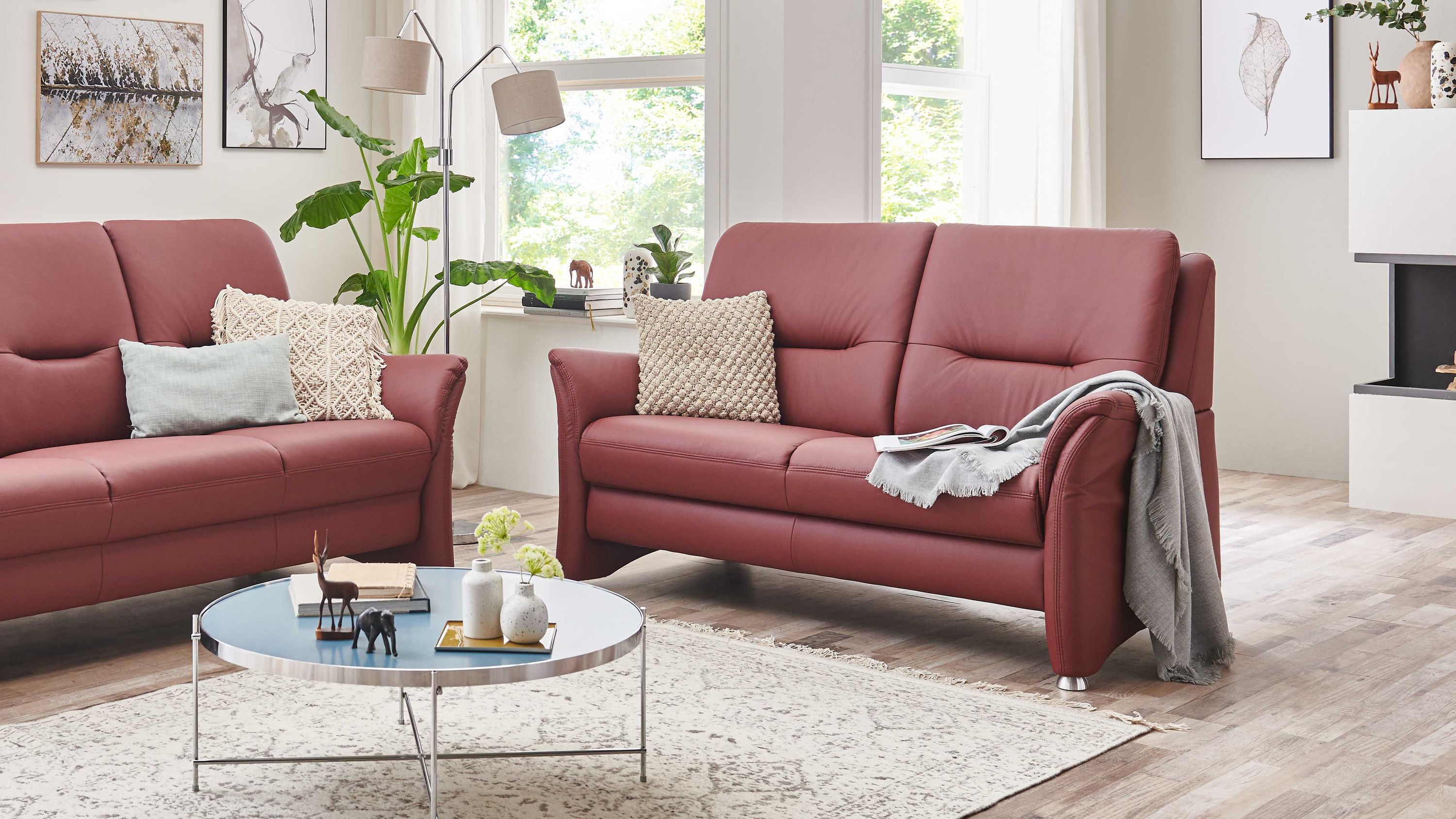 Zweisitziges Ledersofa in brombeerfarben mit Metallfüßen Zweisitziges Sofa in brombeerfarbenem Leder mit Metallfüßen in modernem Wohnzimmer