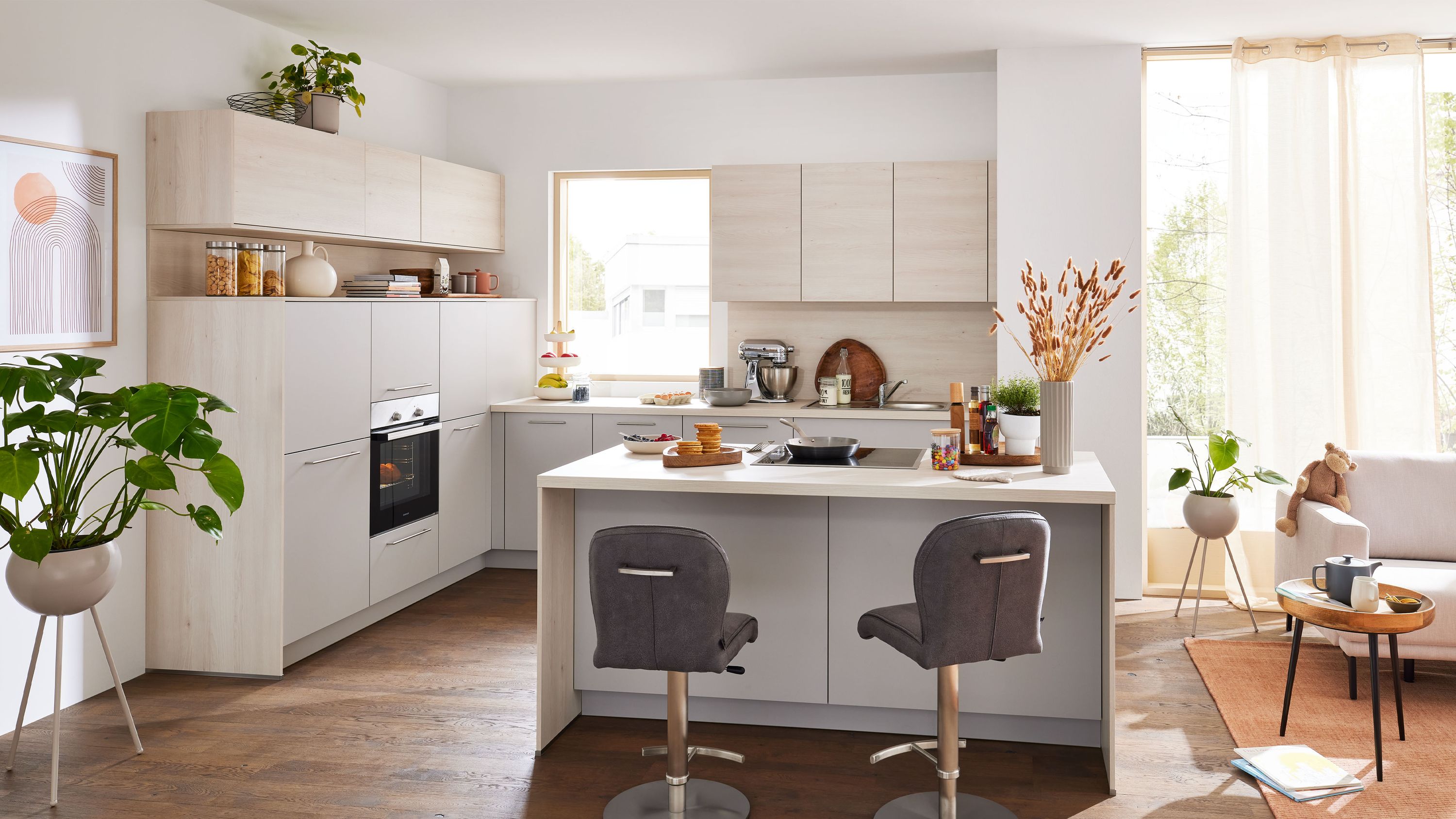 Helle Holzoptik-L-Küche mit Kochinsel und Barhockern. Helle L-Küche in Holzoptik mit Kochinsel Barhockern Einbauofen und großen Fenstern für viel Tageslicht.