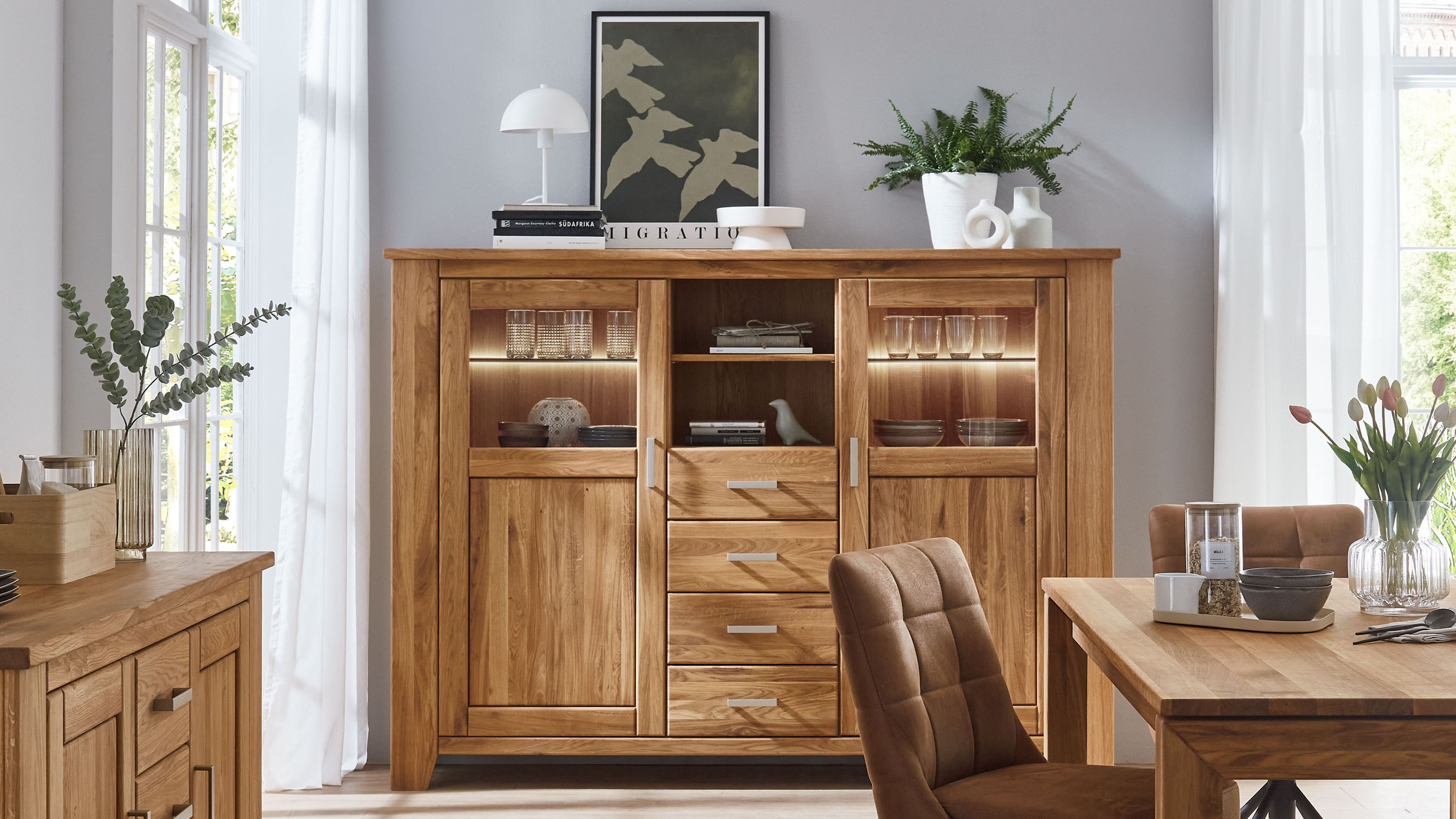 Highboard aus Eiche mit Türen und Schubladen Highboard aus naturfarbener Eiche mit zwei Türen vier Schubladen und Glasfronten mit Beleuchtung