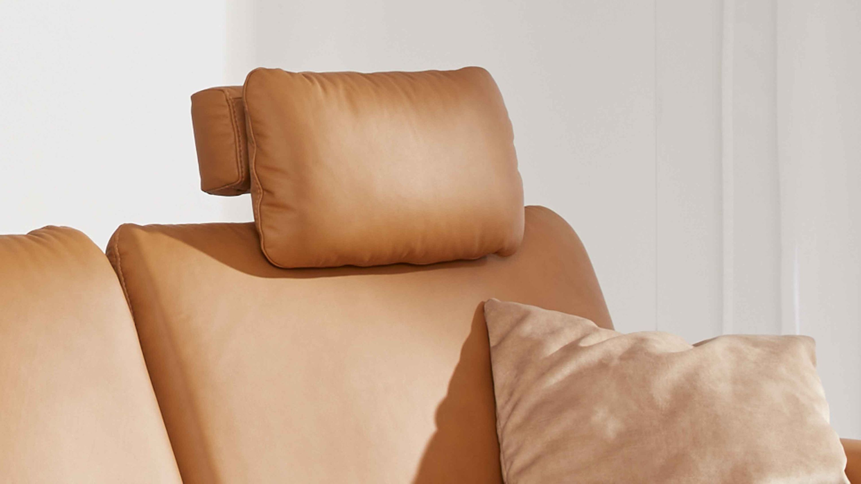 Kopfstütze in kurkumafarbenem Leder auf einem Sofa mit einem Kissen daneben