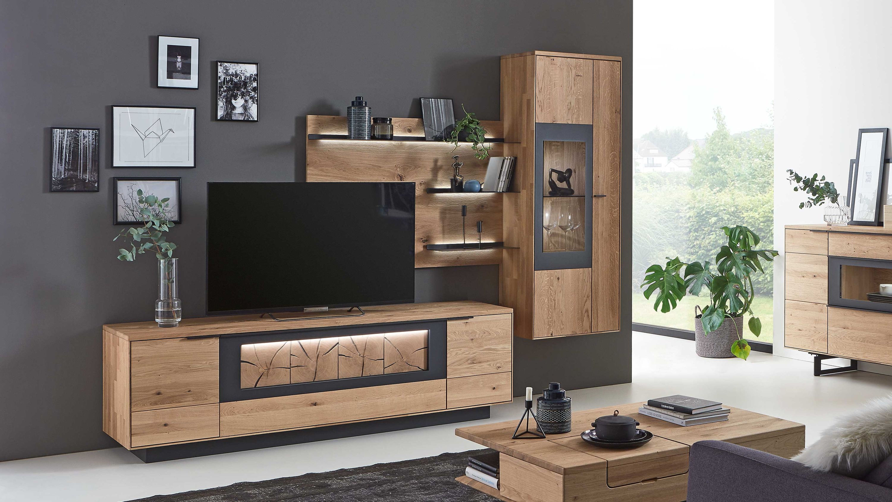 Dreiteilige Wohnwand aus hellem Holz mit TV-Board und Vitrine Dreiteilige Wohnwand aus hellem Holz mit TV-Board Wandregal und Vitrine mit Glastür vor grauer Wand