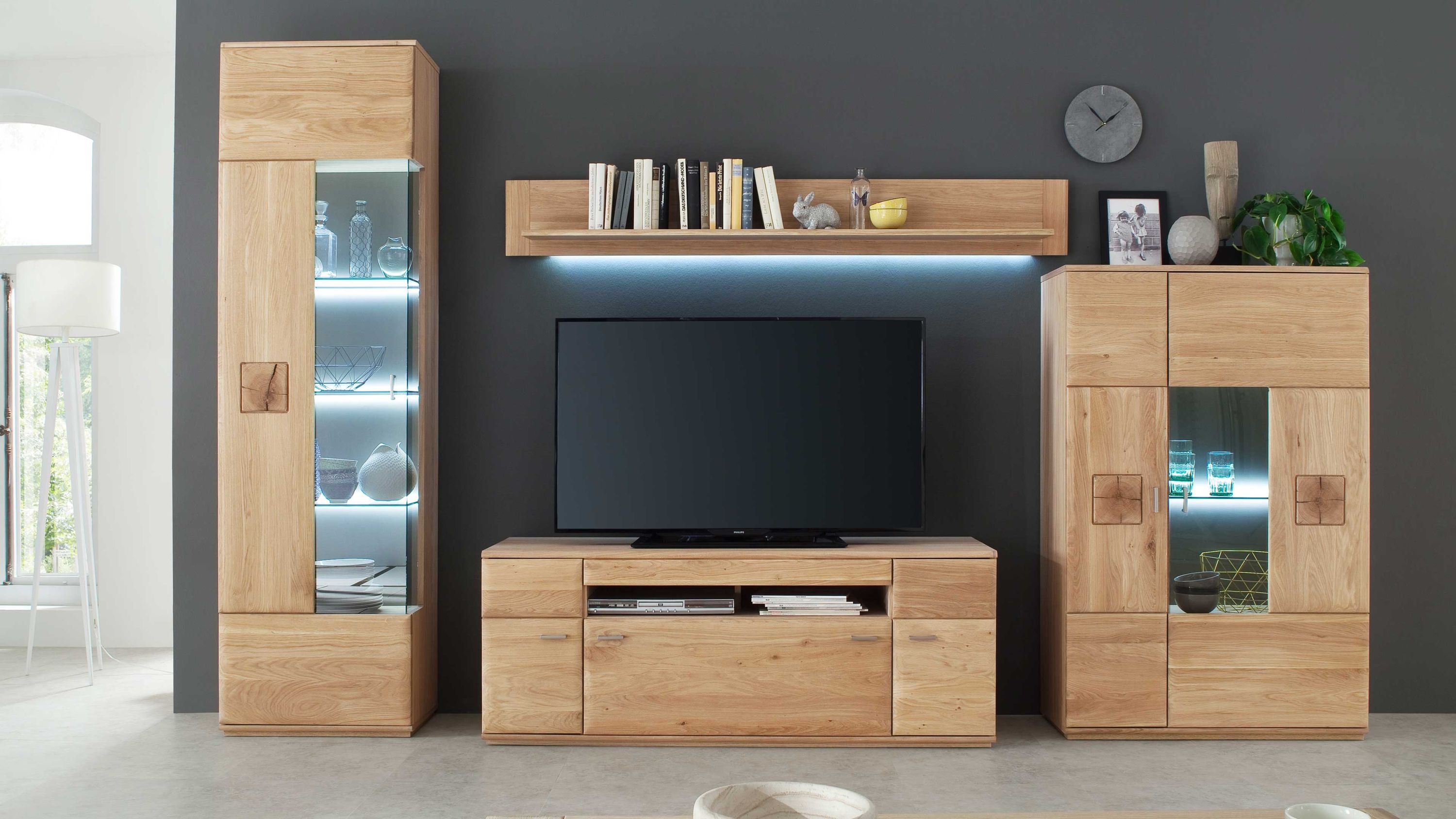 Vierteilige Wohnwand aus hellem Holz mit Vitrine TV-Board Hängeregal und Schrank vor dunkler Wand