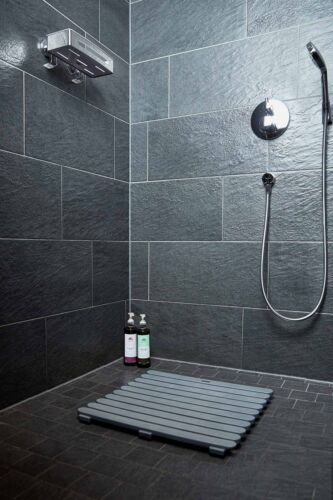 Duschbereich mit Duschrost und moderner Ausstattung Duschrost auf dunklem Fliesenboden, darüber Regendusche und Handbrause, moderner Duschbereich frontal aufgenommen