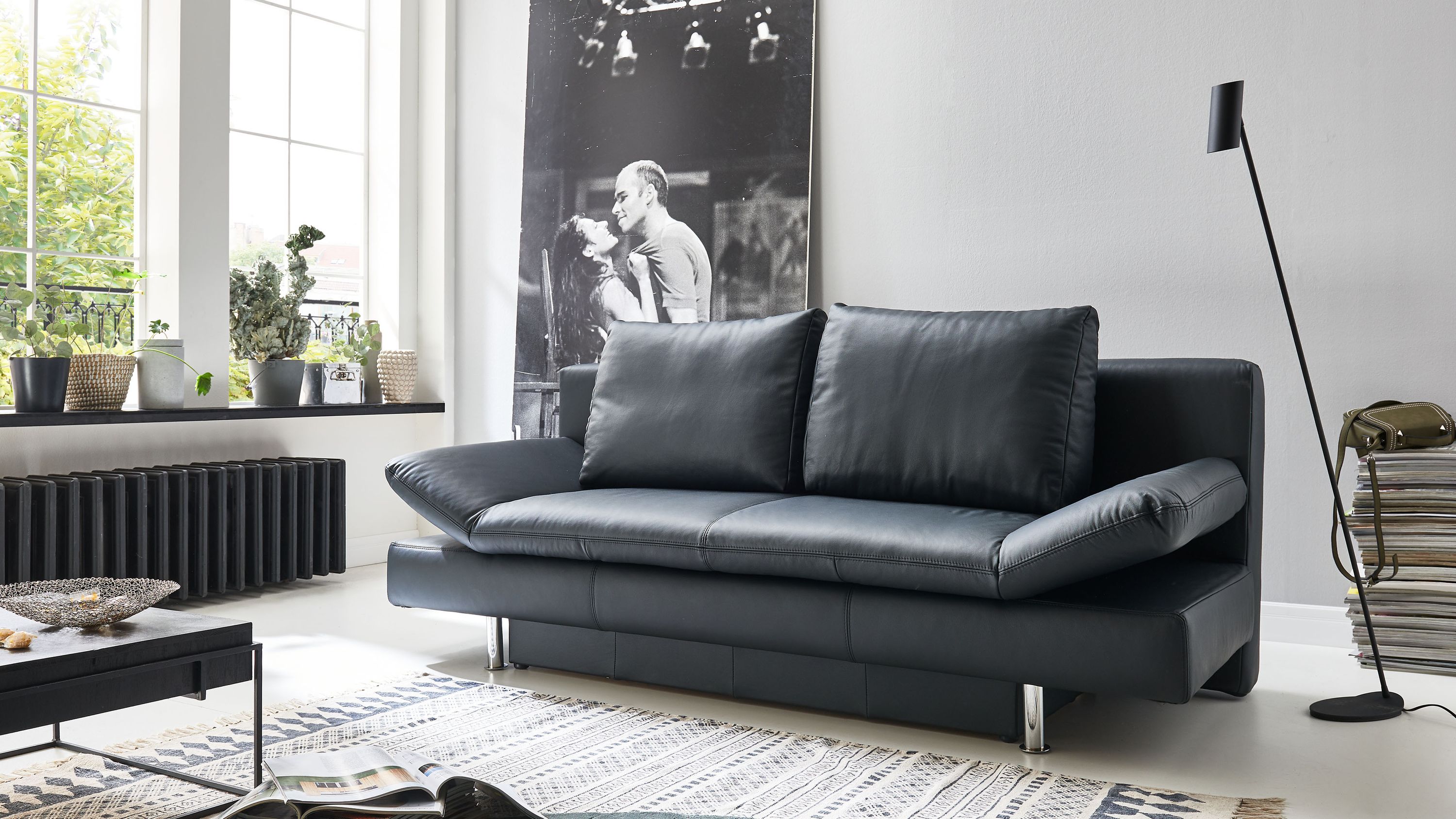 Schwarzes Schlafsofa mit verchromten Metallfüßen und zwei Rückenpolstern in modernem Wohnzimmer