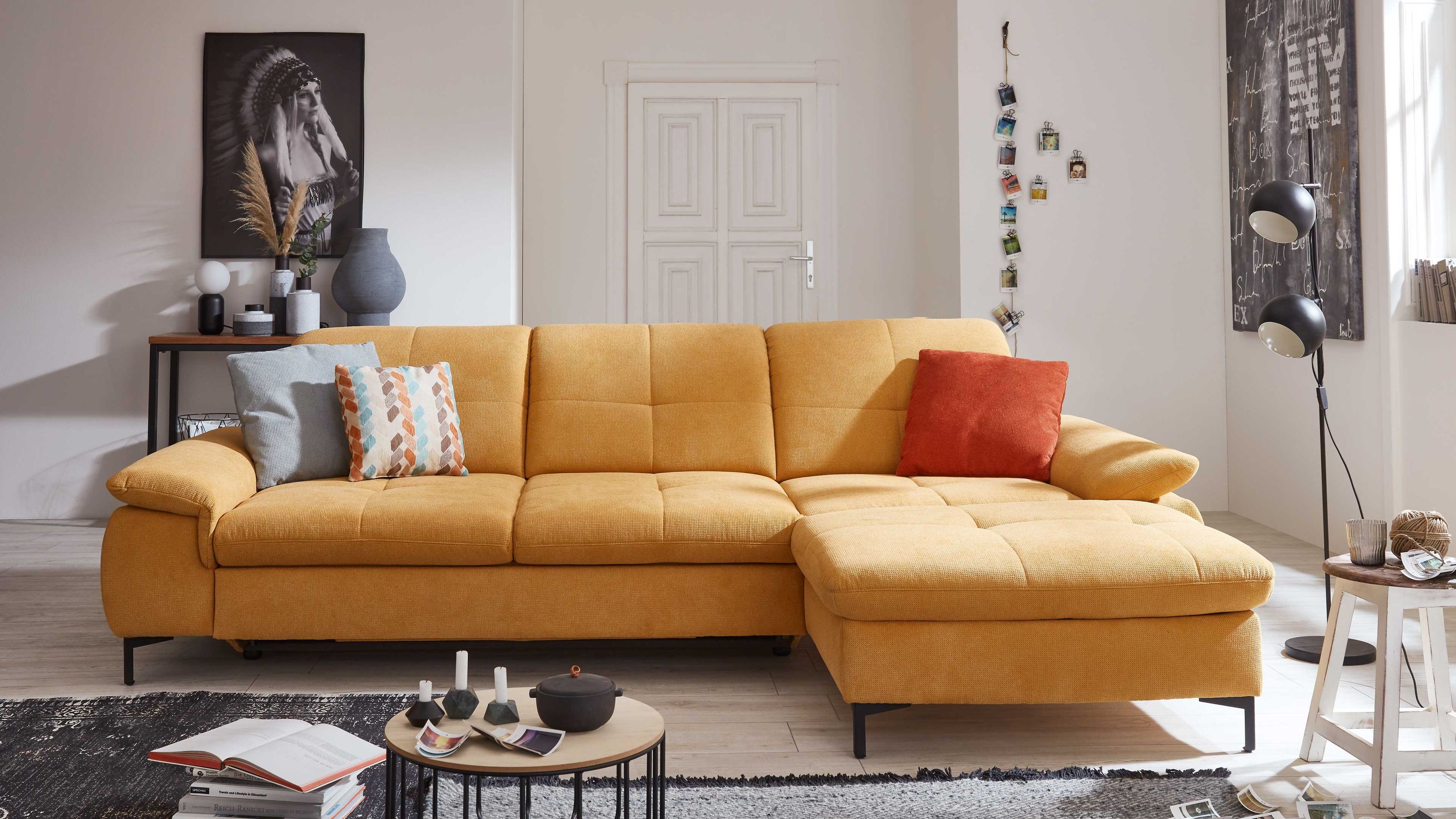 Ecksofa in Goldgelb mit Kissen Ecksofa mit goldgelbem Stoffbezug und schwarzen Füßen mit drei Kissen in Blau Muster und Rot