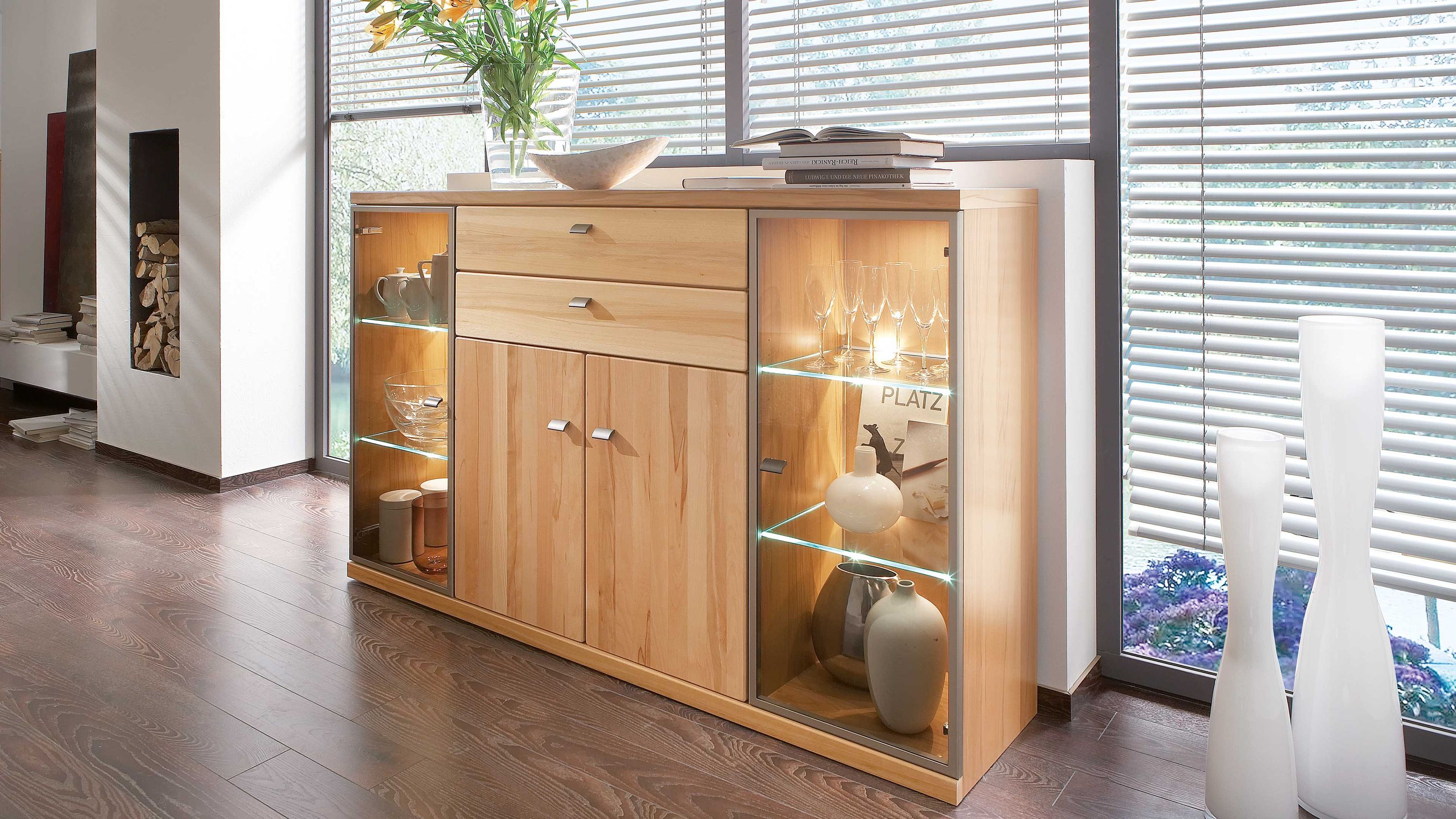 Helles Highboard mit vier Türen zwei Schubladen und zwei seitlichen Glasvitrinen mit Beleuchtung