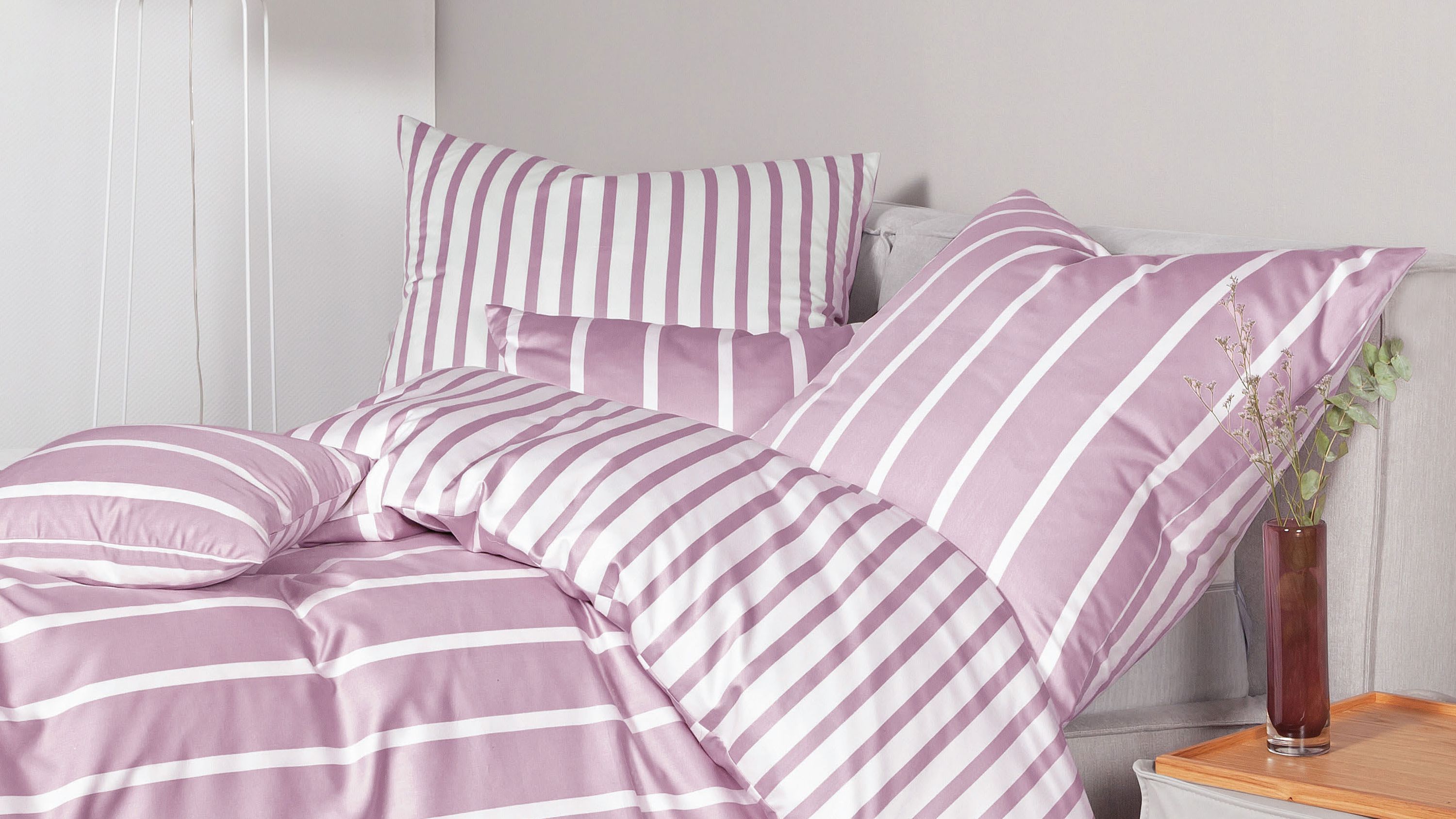 Bettwäsche-Set mit weißen und rosa Streifen auf Bett und Kissen