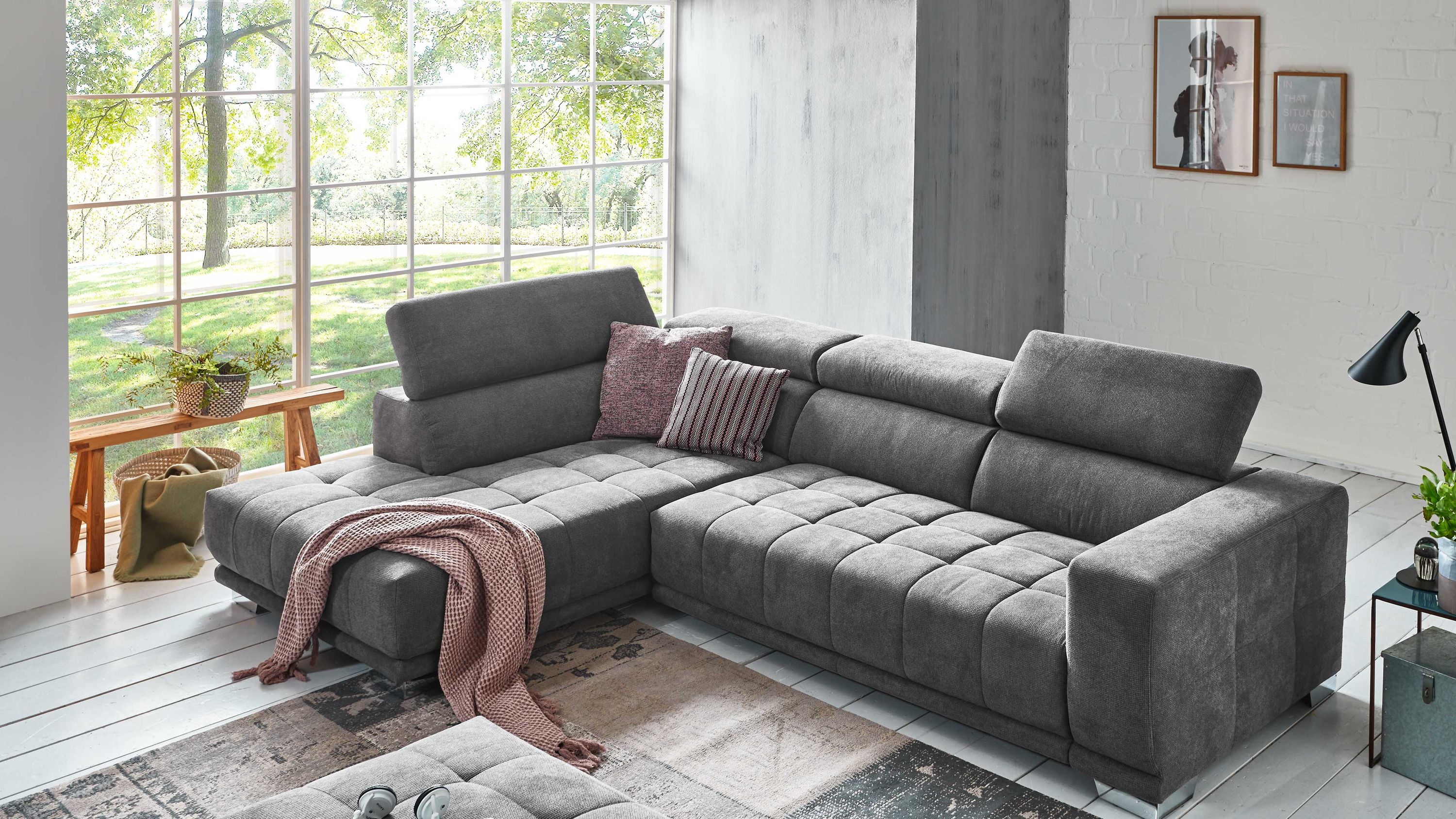Anthrazitfarbenes Ecksofa mit verstellbaren Kopfstützen und zwei Kissen in modernem Wohnzimmer