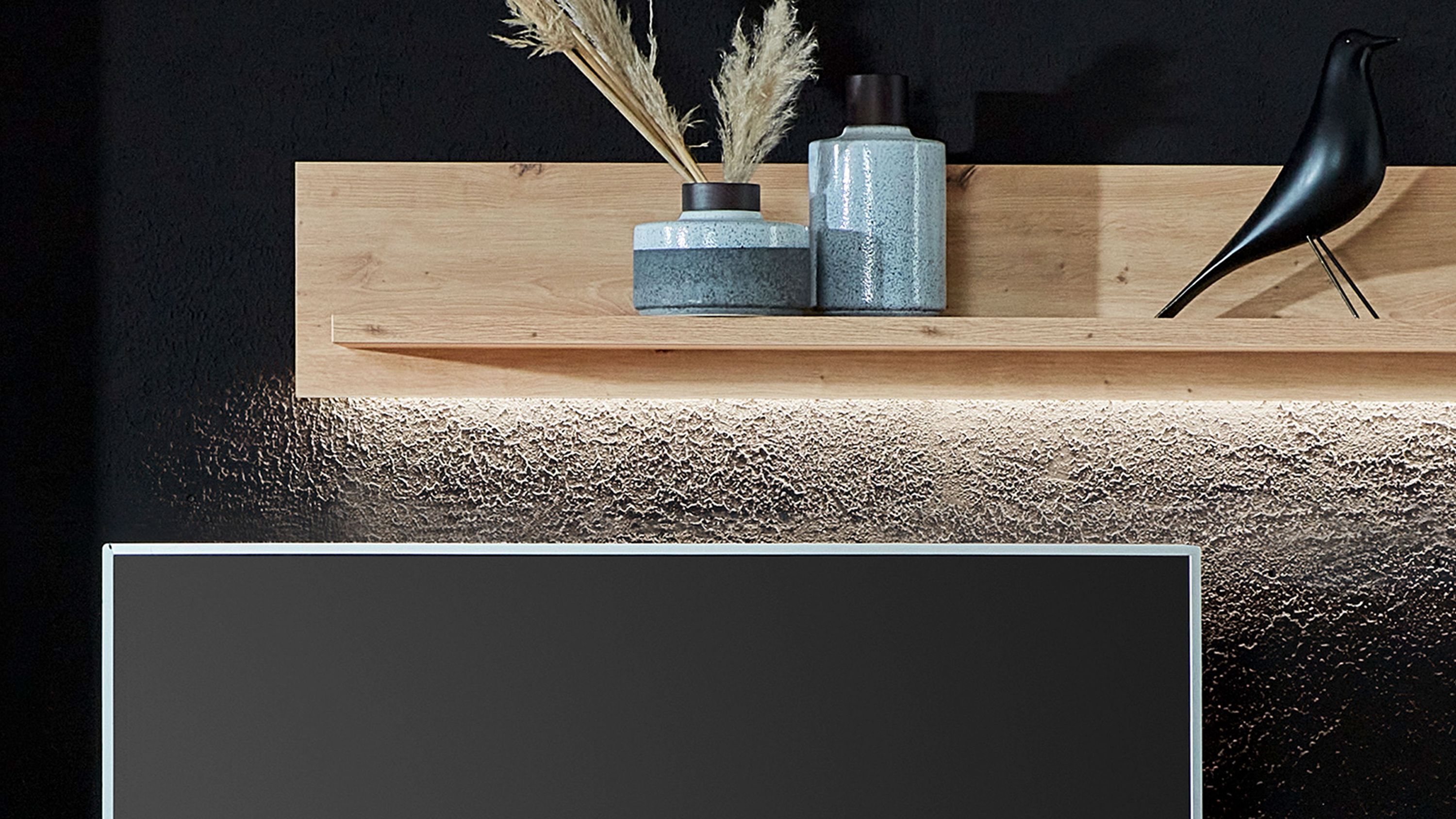 Helles Holz Wandregal mit LED-Beleuchtung an schwarzer Wand dekoriert mit Vasen und schwarzem Vogel