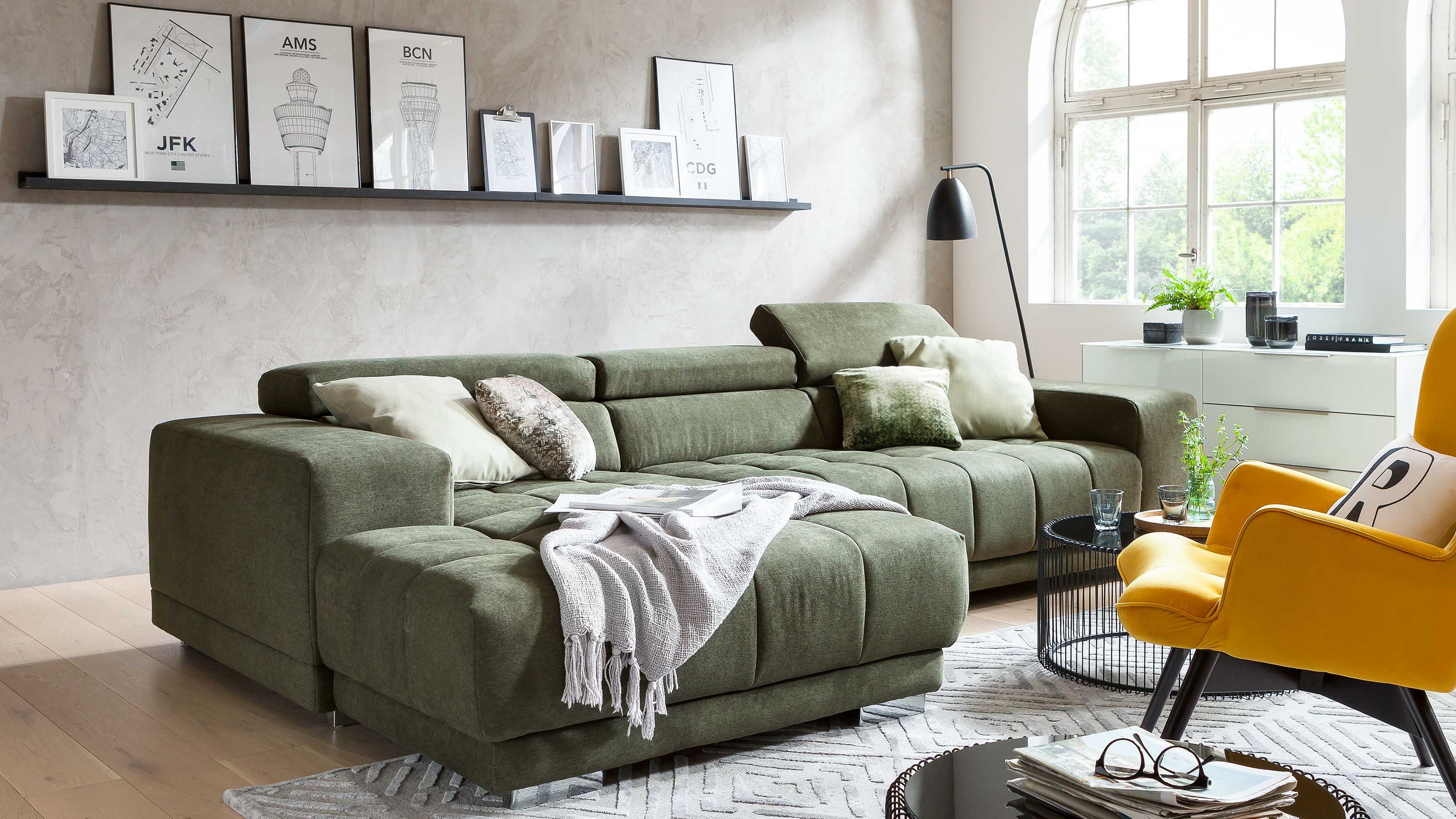 Ecksofa mit moosgrünem Stoffbezug und Metallfüßen in modernem Wohnzimmer mit Kissen und Decke