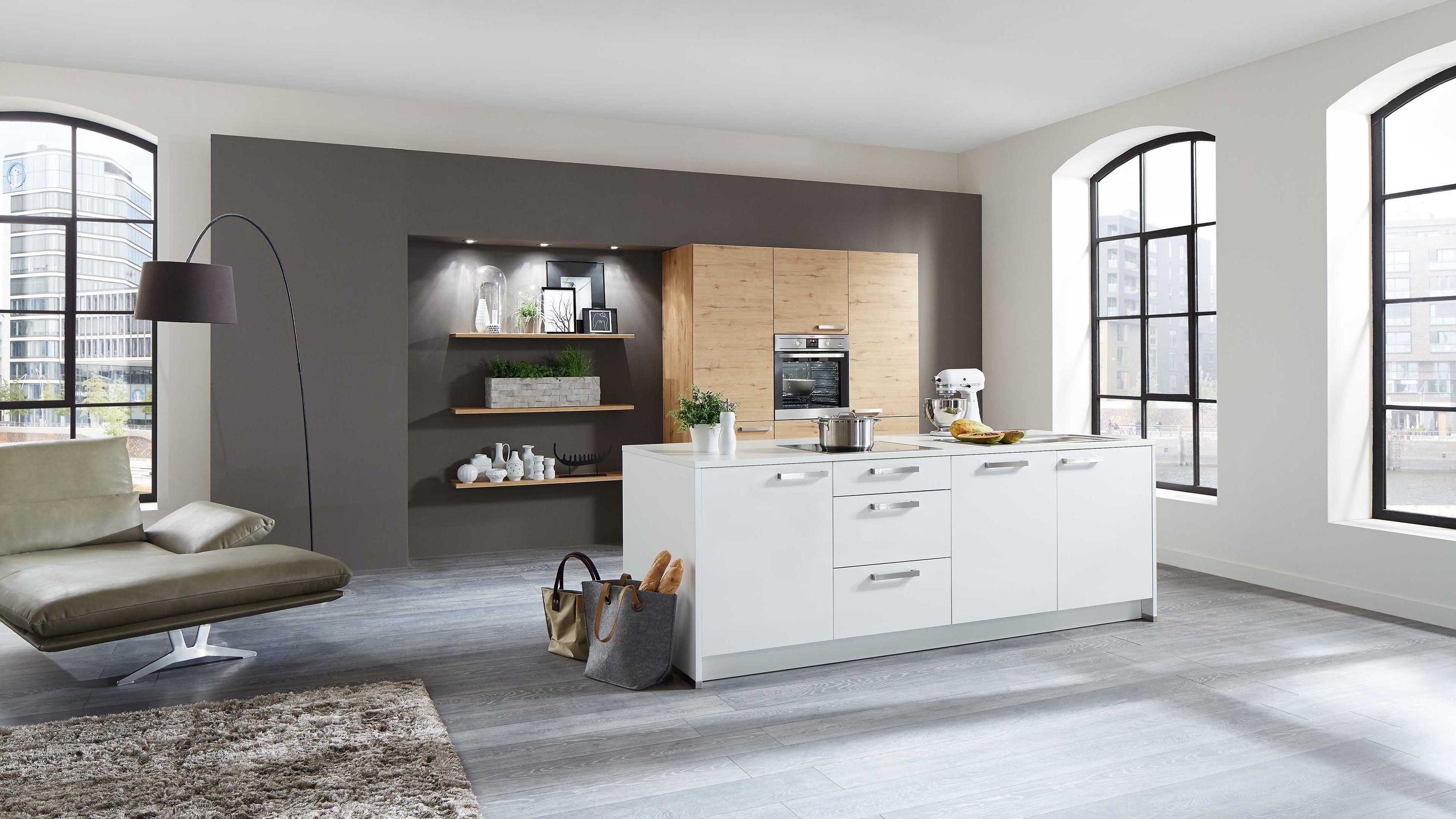 Moderne Küche mit Insel weißen Schränken und gemütlicher Sitzecke Küche mit weißer Insel Edelstahlgeräten offenen Regalen Sitzbereich Tageslicht durch große Fenster