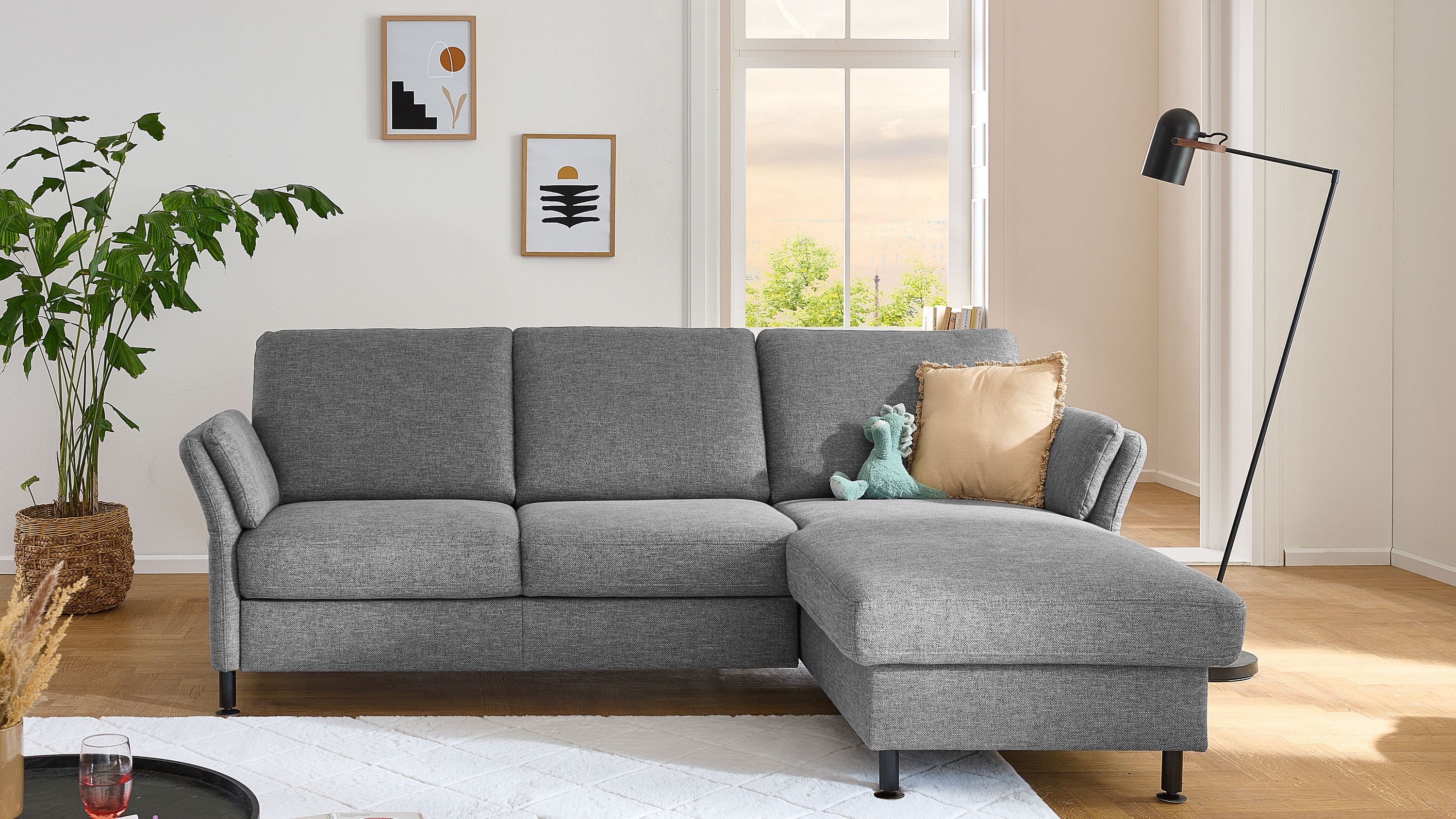 Ecksofa mit drei Rückenlehnen und rechter Ottomane in grauem Flachgewebe mit schwarzen Metallfüßen