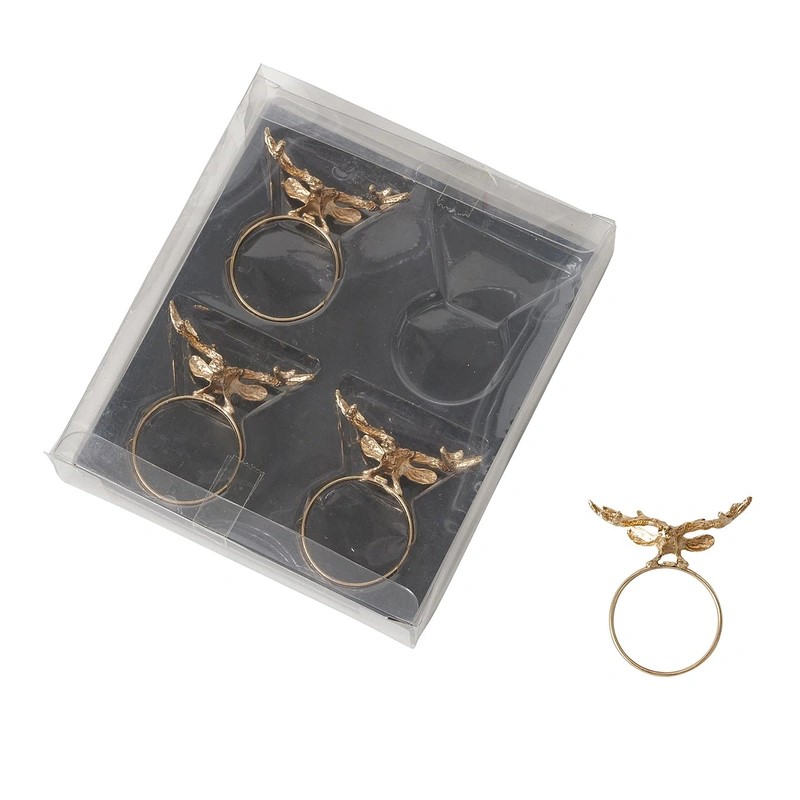 Vier goldene Serviettenringe mit Flügeldesign in transparenter Verpackung ein Ring daneben Vogelperspektive