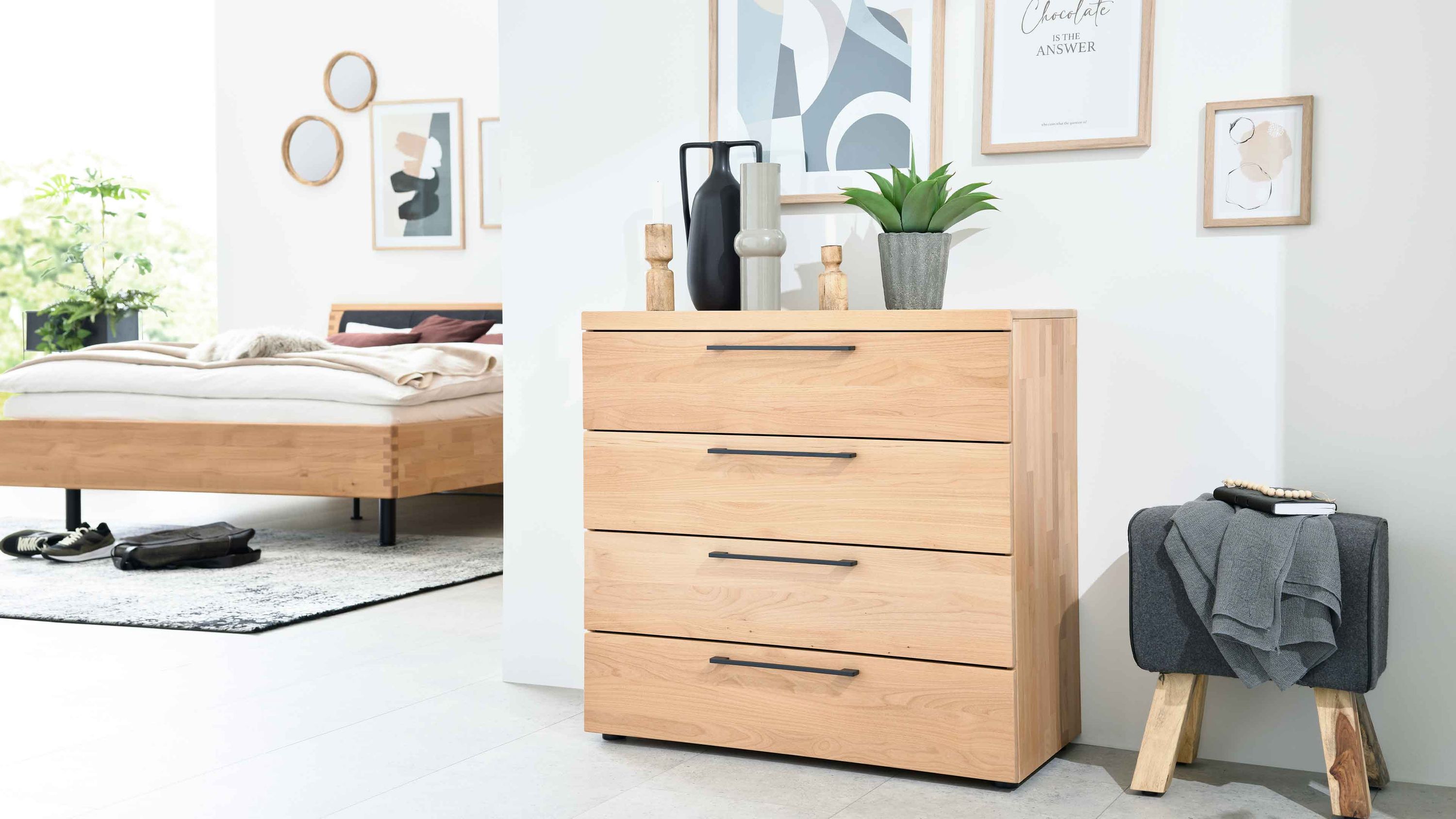 Kommode mit vier Schubladen in hellbrauner Holzoptik mit schwarzen Griffen in modernem Schlafzimmer