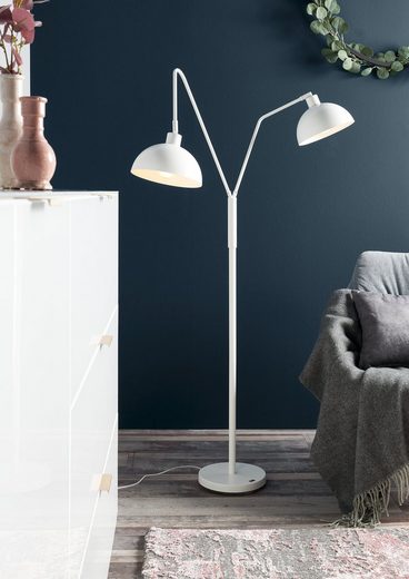 Seidenweiße Aluminium-Stehlampe mit flachem Kopf  seitlich inszeniert neben Sofa im hellen Wohnambiente