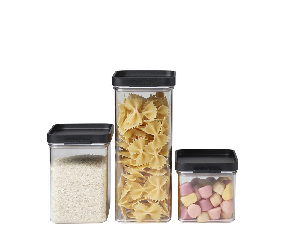 Drei transparente Dosen mit schwarzem Deckel, gefüllt mit Reis, Pasta und bunten Süßigkeiten, nebeneinander platziert