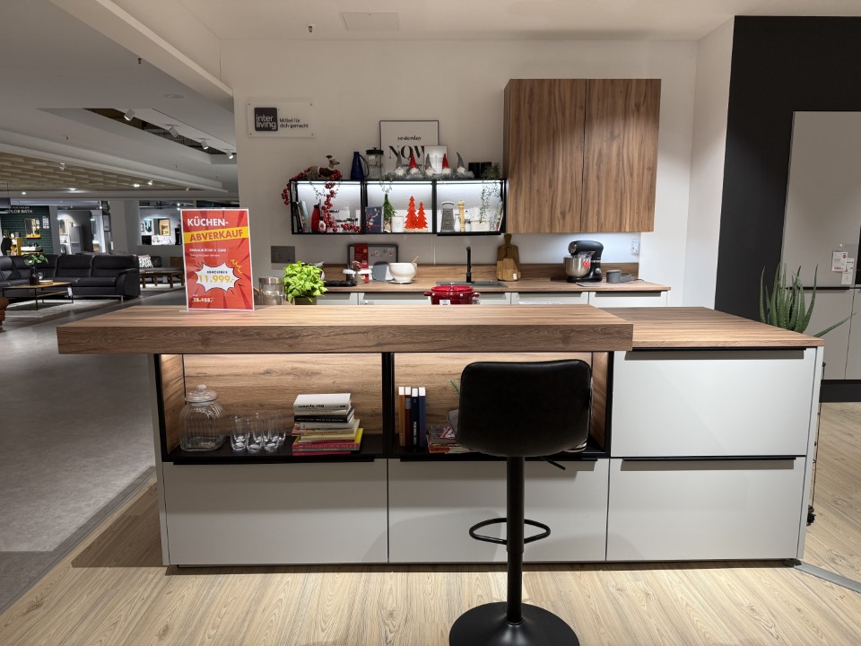 Moderne Küche mit zentraler Insel, Holzarbeitsplatte und offenen Regalen, dahinter Schränke mit Holzfronten