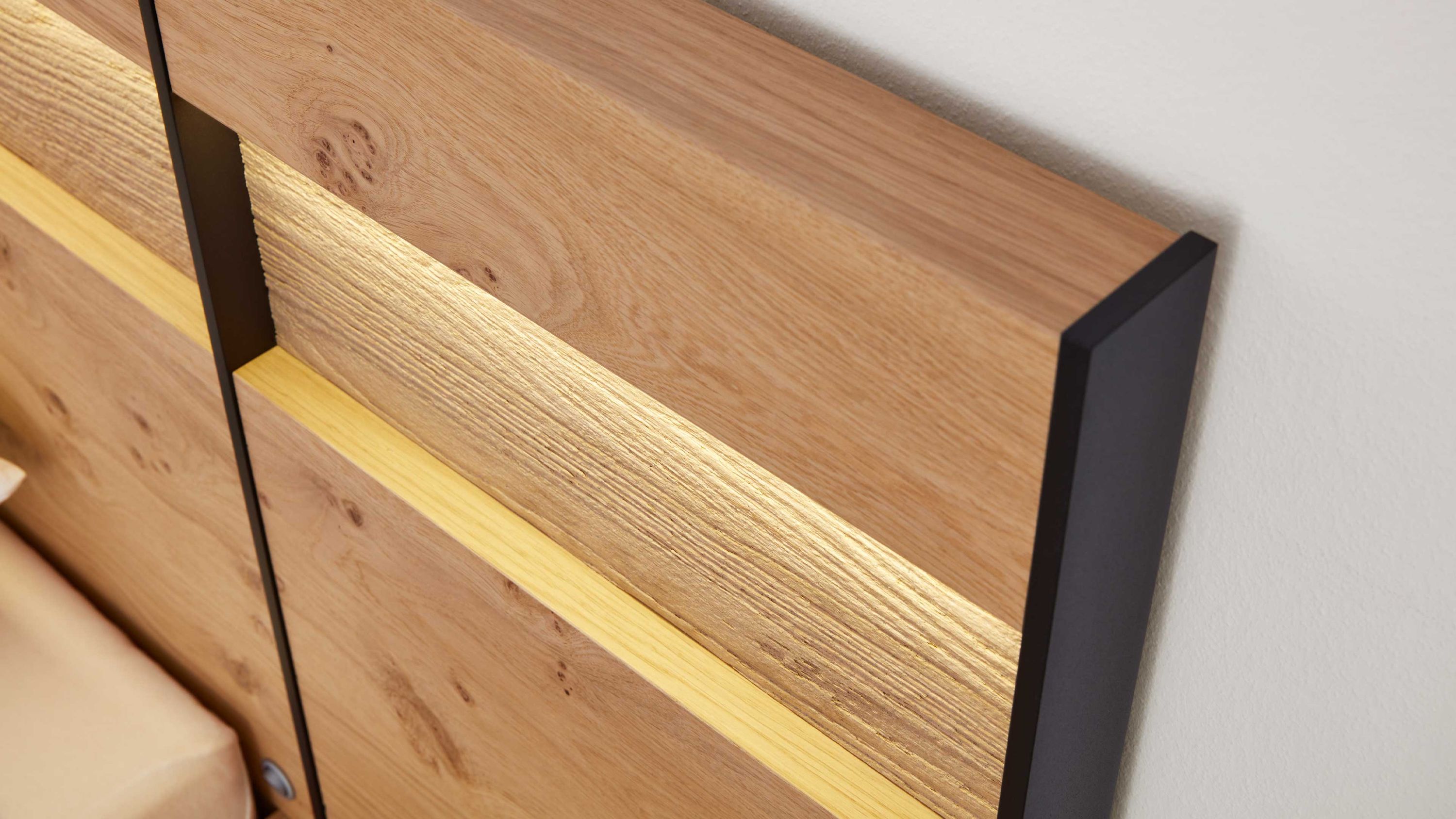 Holzpaneel mit integrierter LED-Beleuchtung und schwarzen Seitenkanten an einer Wand