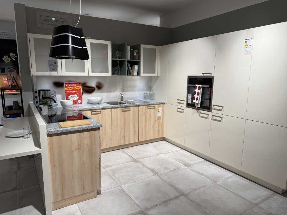 Moderne Küchenzeile mit weißen und hellen Holzschränken, grauer Arbeitsplatte und eingebautem Backofen