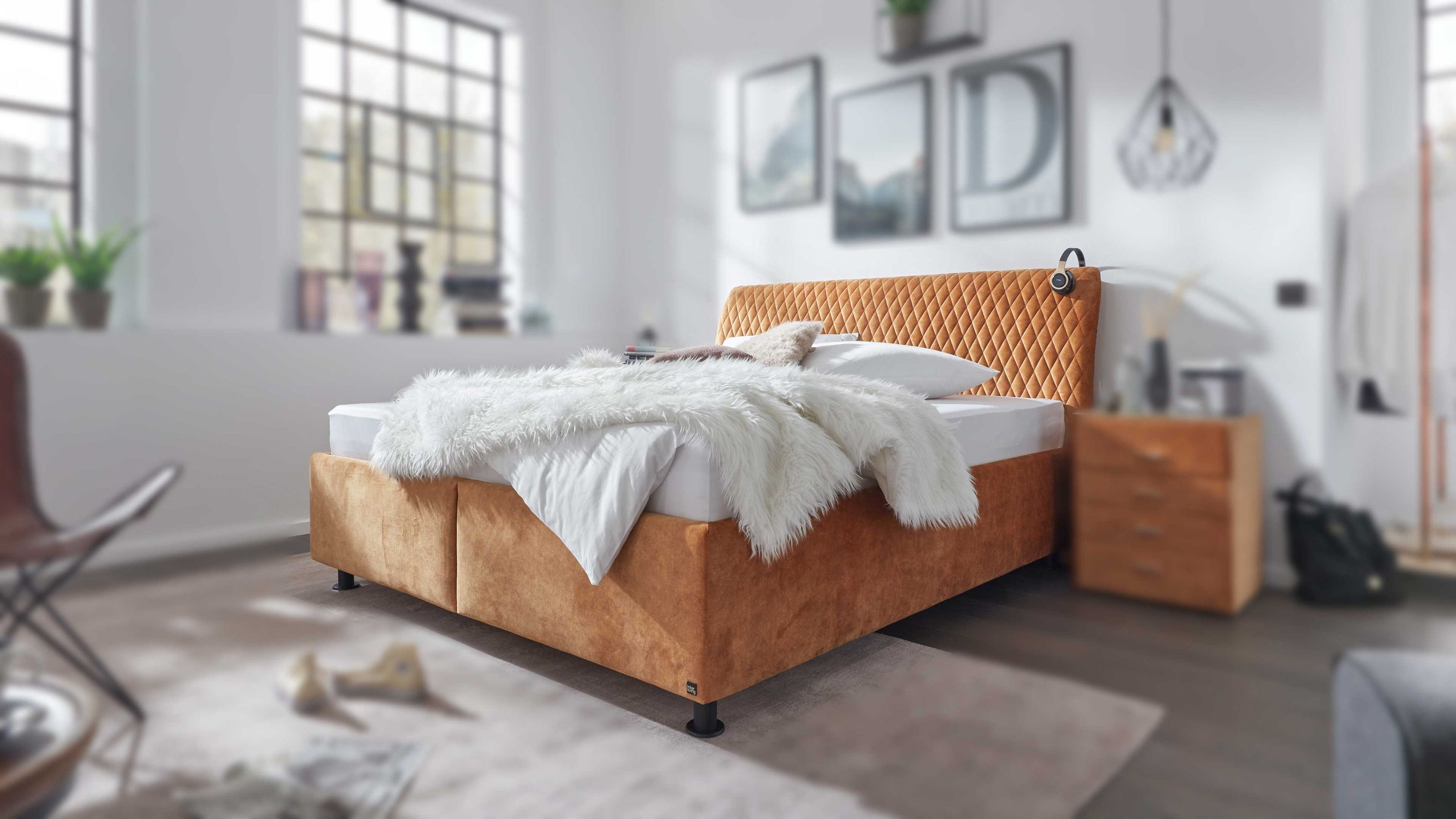 Polsterbett mit gestepptem Kopfteil und goldfarbenem Bezug in modernem Schlafzimmer