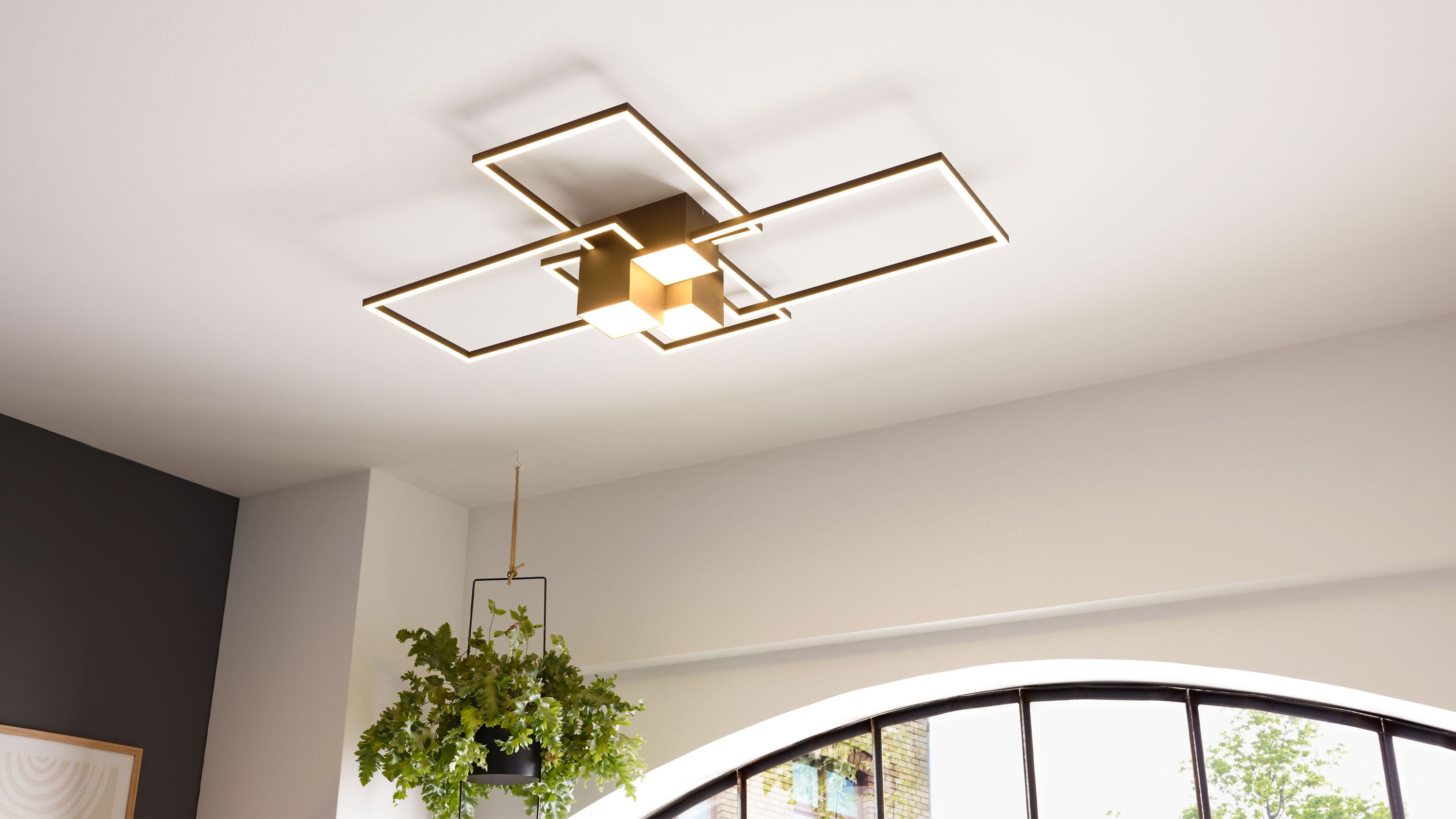 Deckenlampe mit schwarzen rechteckigen Metallrahmen und zentralen Leuchtwürfeln an weißer Decke