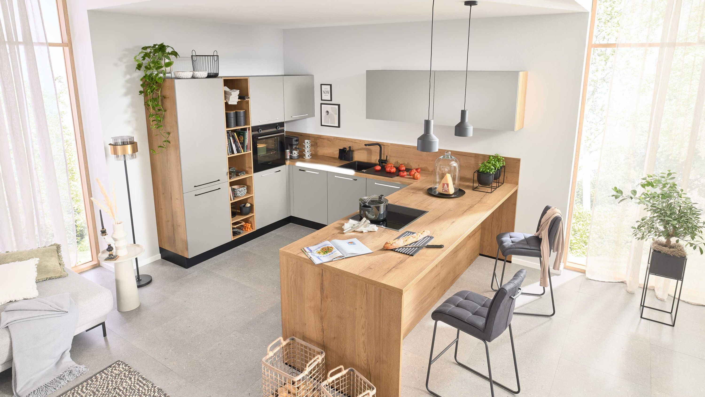 Moderne L-Küche mit Holzfronten weißen Oberflächen Hängelampen Barhockern und großen Fenstern bei Tageslicht