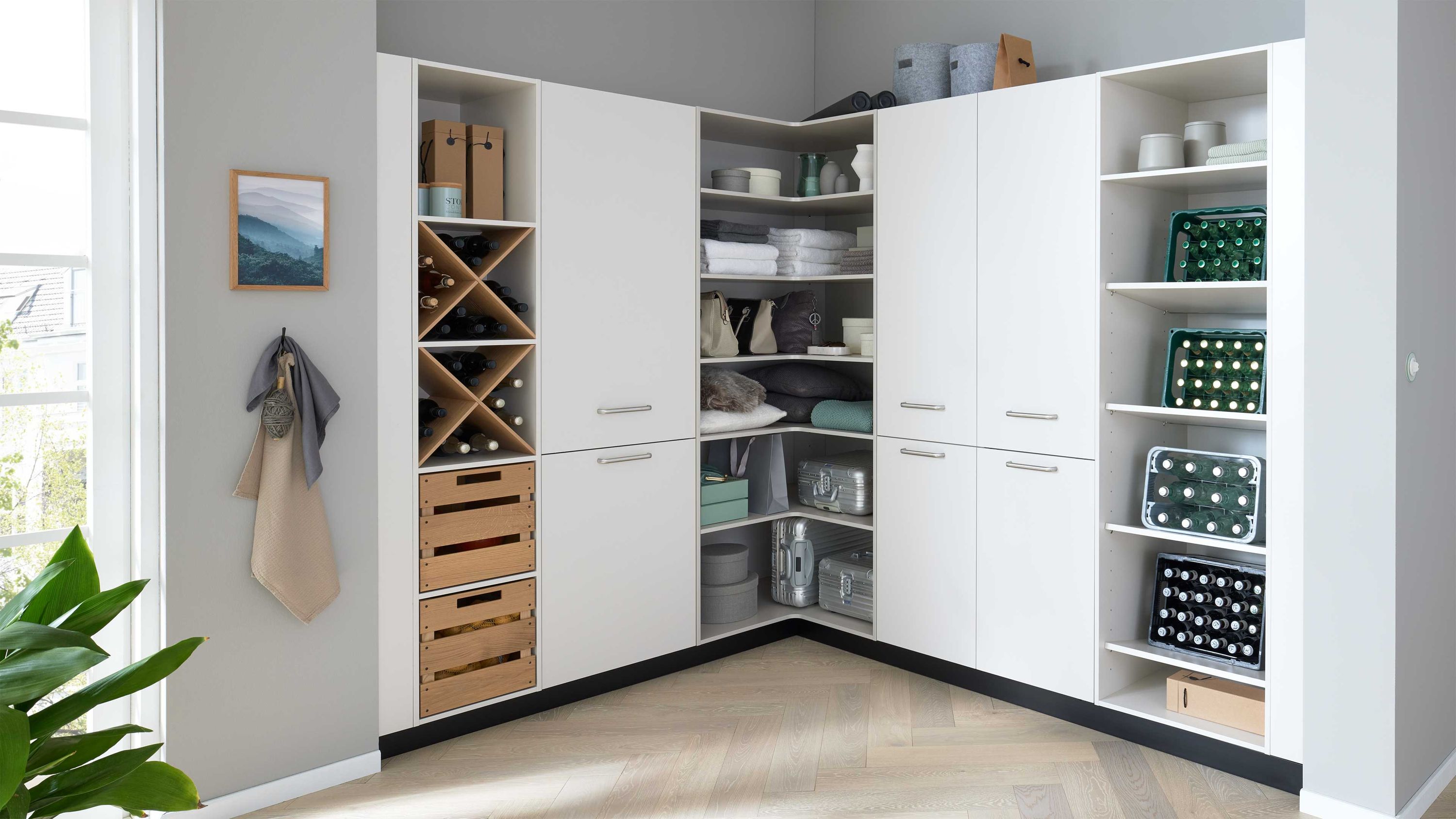 Eckschrank mit Regalsystem Stauraum und Weinhalter Eckregal mit weißen Schränken offenen Fächern Körben Kleidung Weinhaltern Licht durch Fenster links