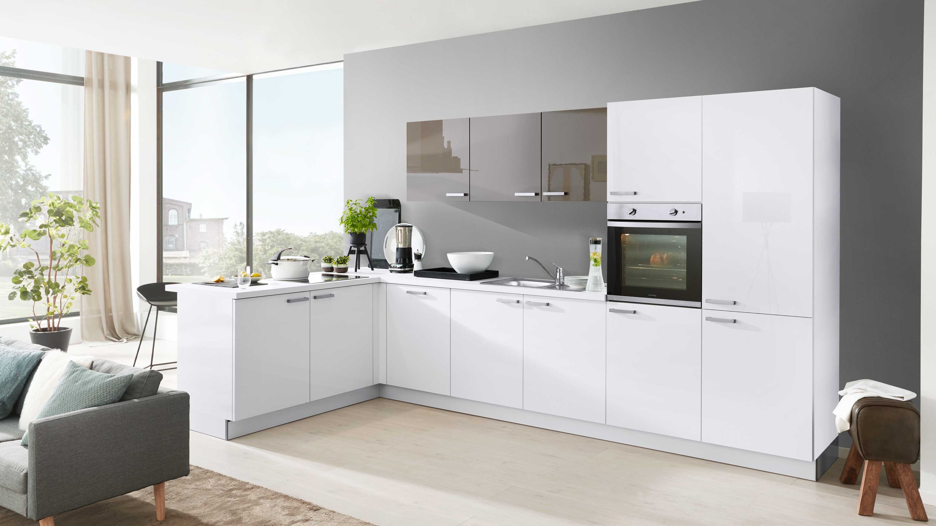 Helle L-Küche mit Wohnbereich funktionalem Design und natürlichem Lichteinfall Weiße L-Küche mit grauer Wand Einbauofen Fensterlicht Kaffeemaschine Pflanzen Wohnbereich mit Sofa links