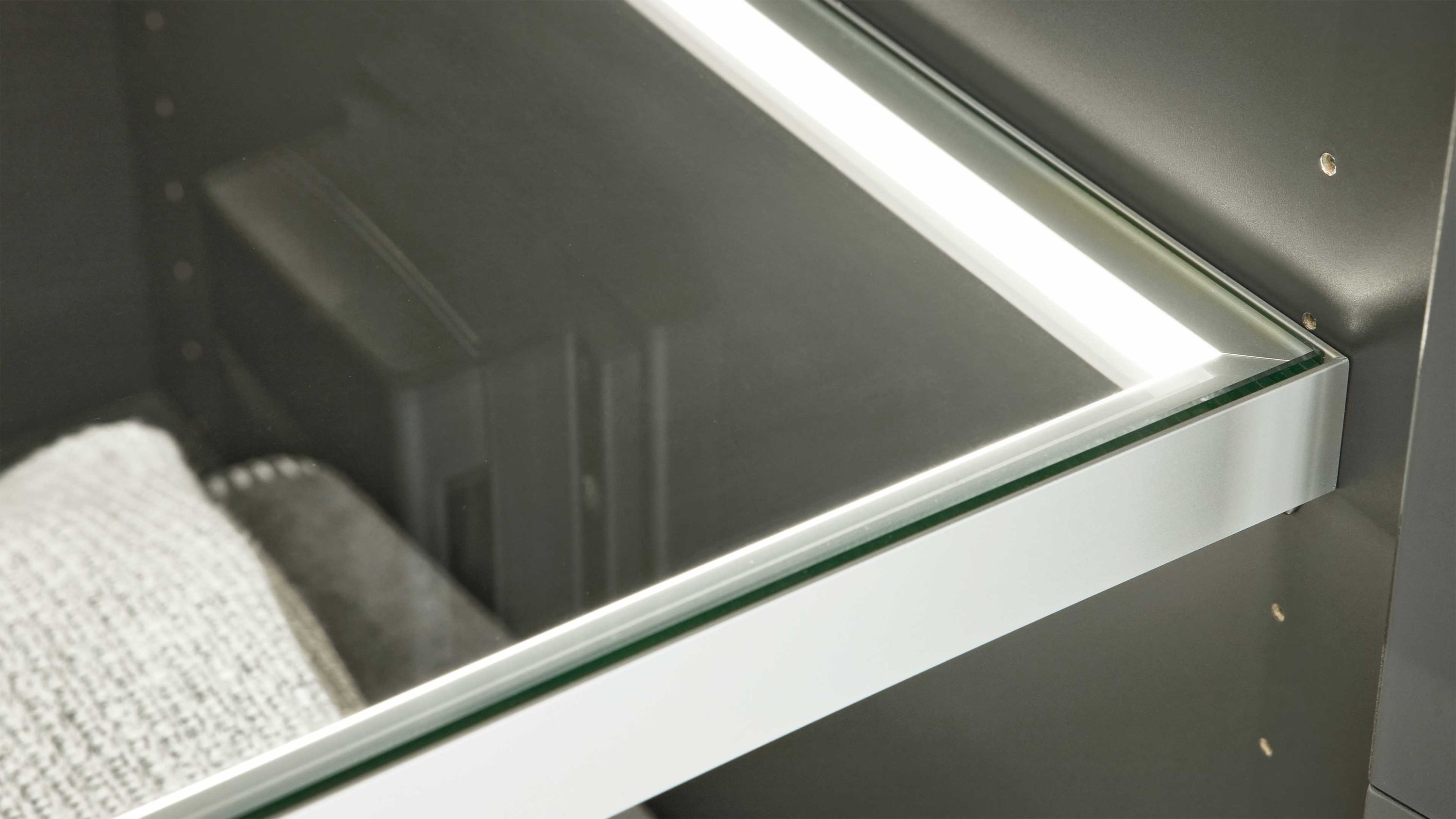 Glasboden mit weißer LED-Beleuchtung in einem Möbelstück mit grauen Seitenwänden