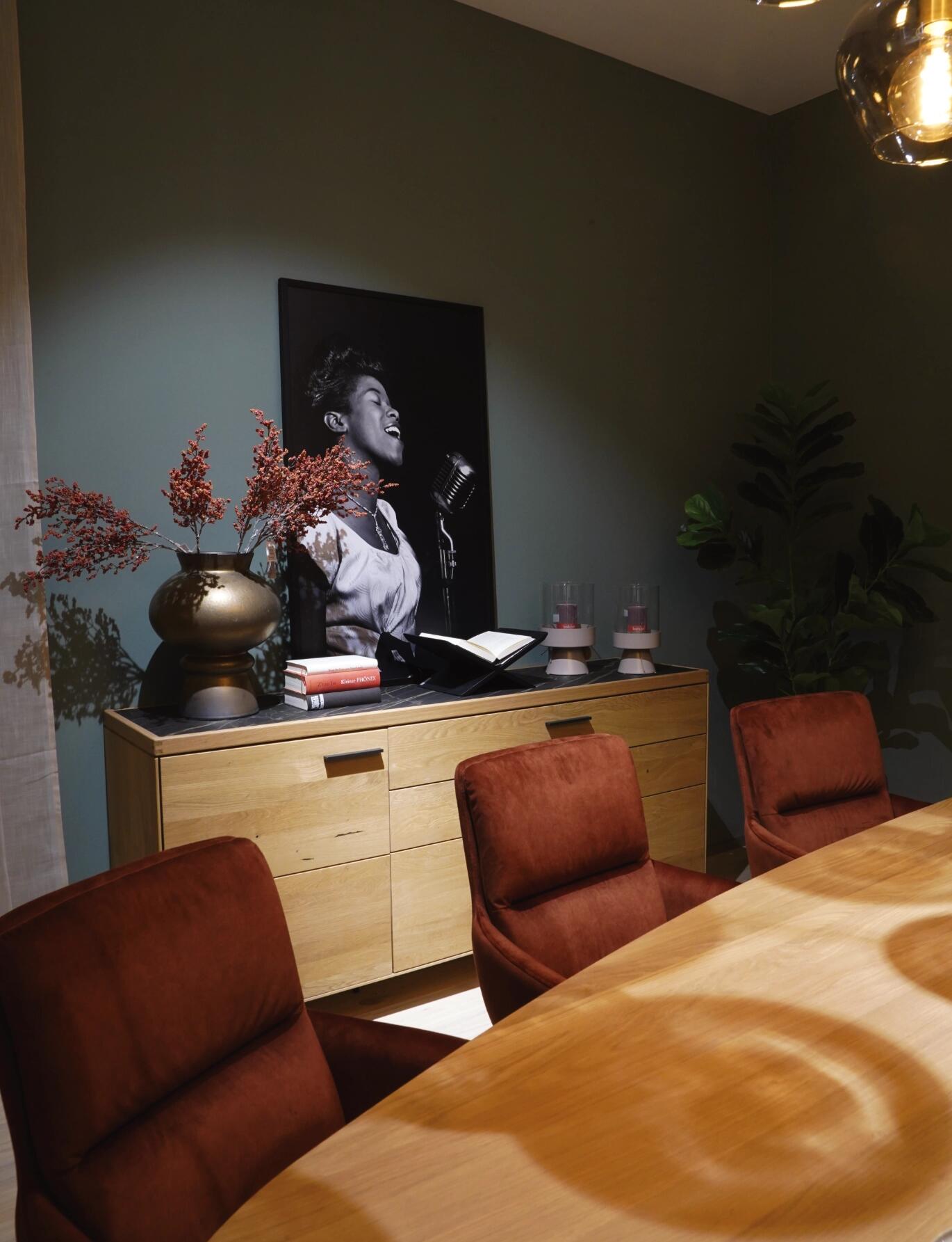 Moderner Essbereich mit Holztisch, gepolsterten Stühlen, Sideboard und stimmungsvoller Beleuchtung.