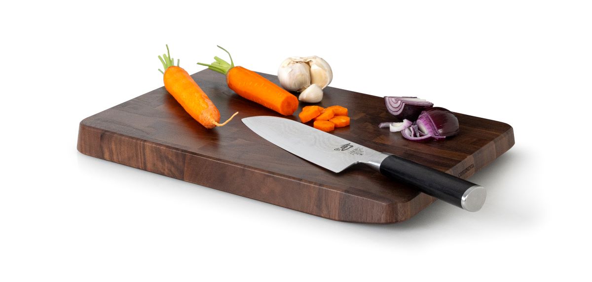 Schneidebrett mit Messer Karotten Knoblauch und gehackter Zwiebel 38×25×3?cm leicht schräg von oben rechts aufgenommen